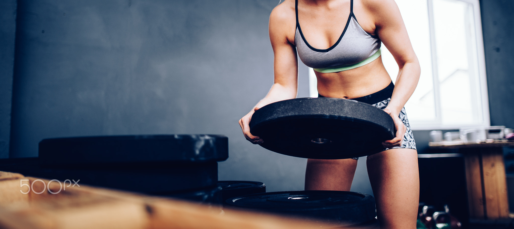 Young girl lifting weights during crossfit training at the gym