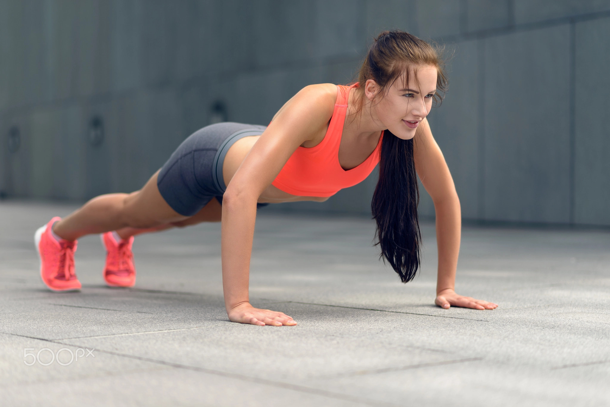 Fit young woman doing push-ups in town