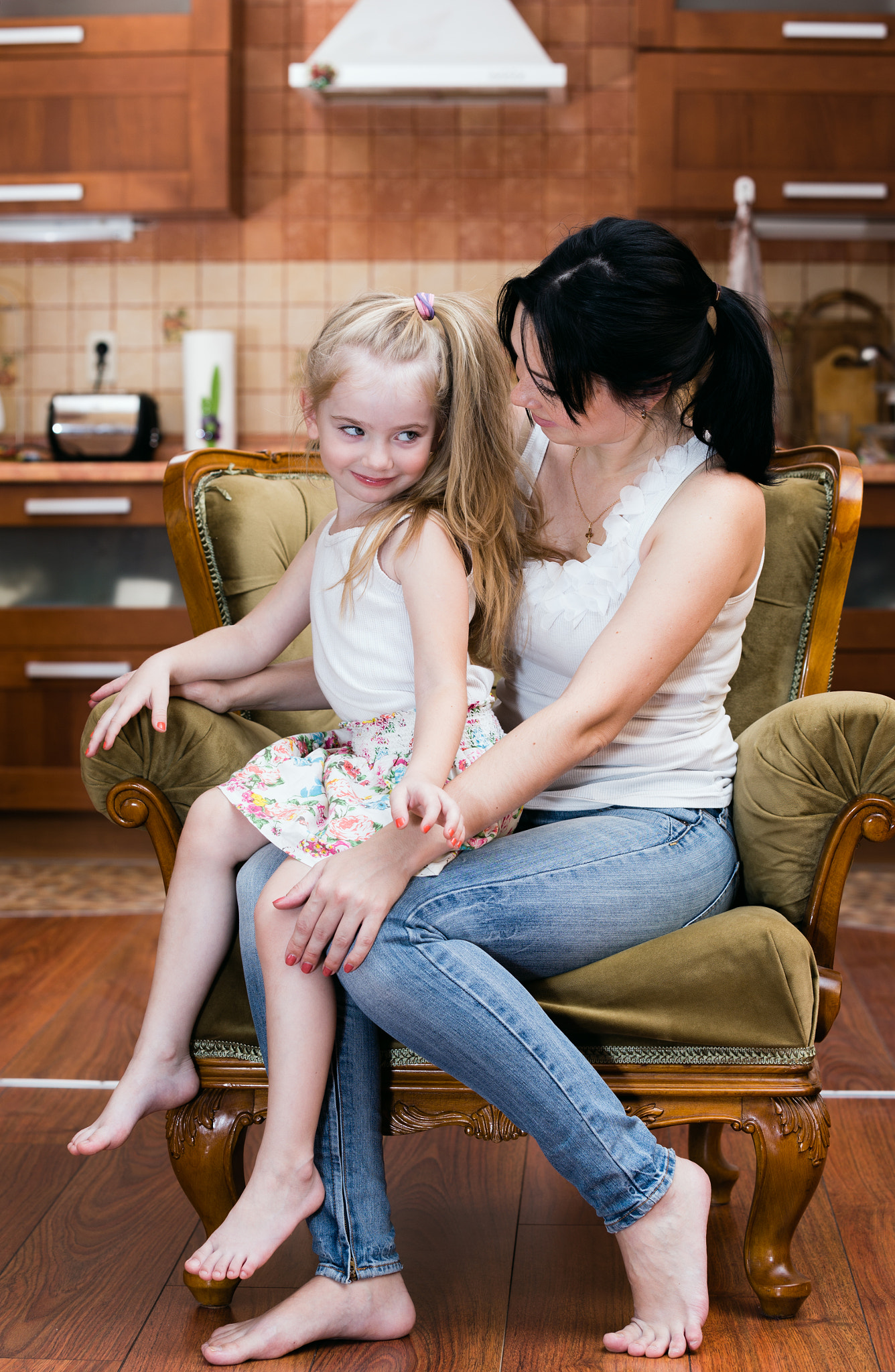 Mother and her little daughter sitting in a chair