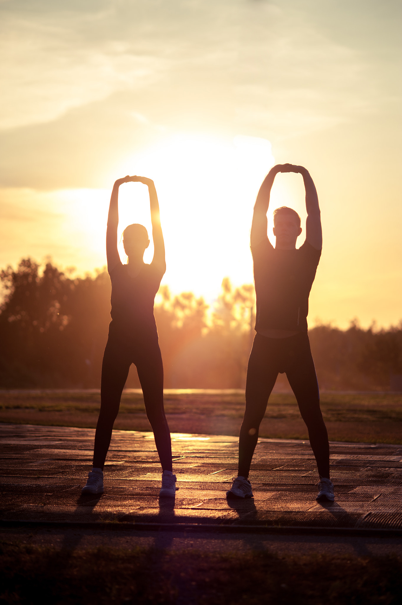 Nikon D700 + AF Micro-Nikkor 105mm f/2.8 sample photo. Two silhouettes of young adults doing warming up exercises at su photography