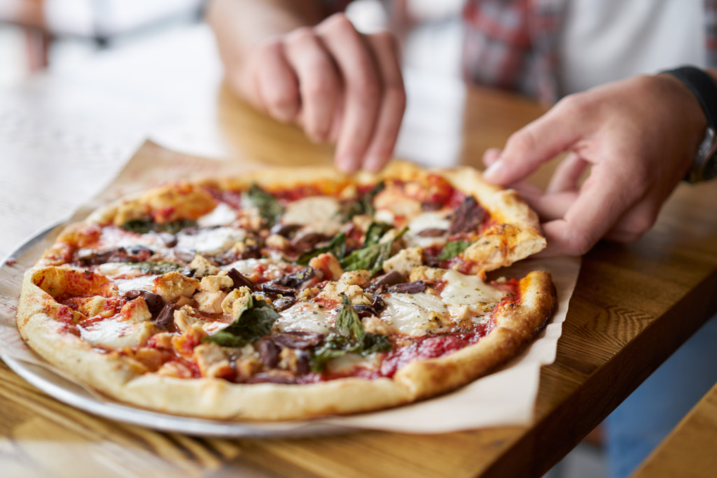 meal time at pizzeria, man taking a slice of the pizza by Joshua Resnick on 500px.com