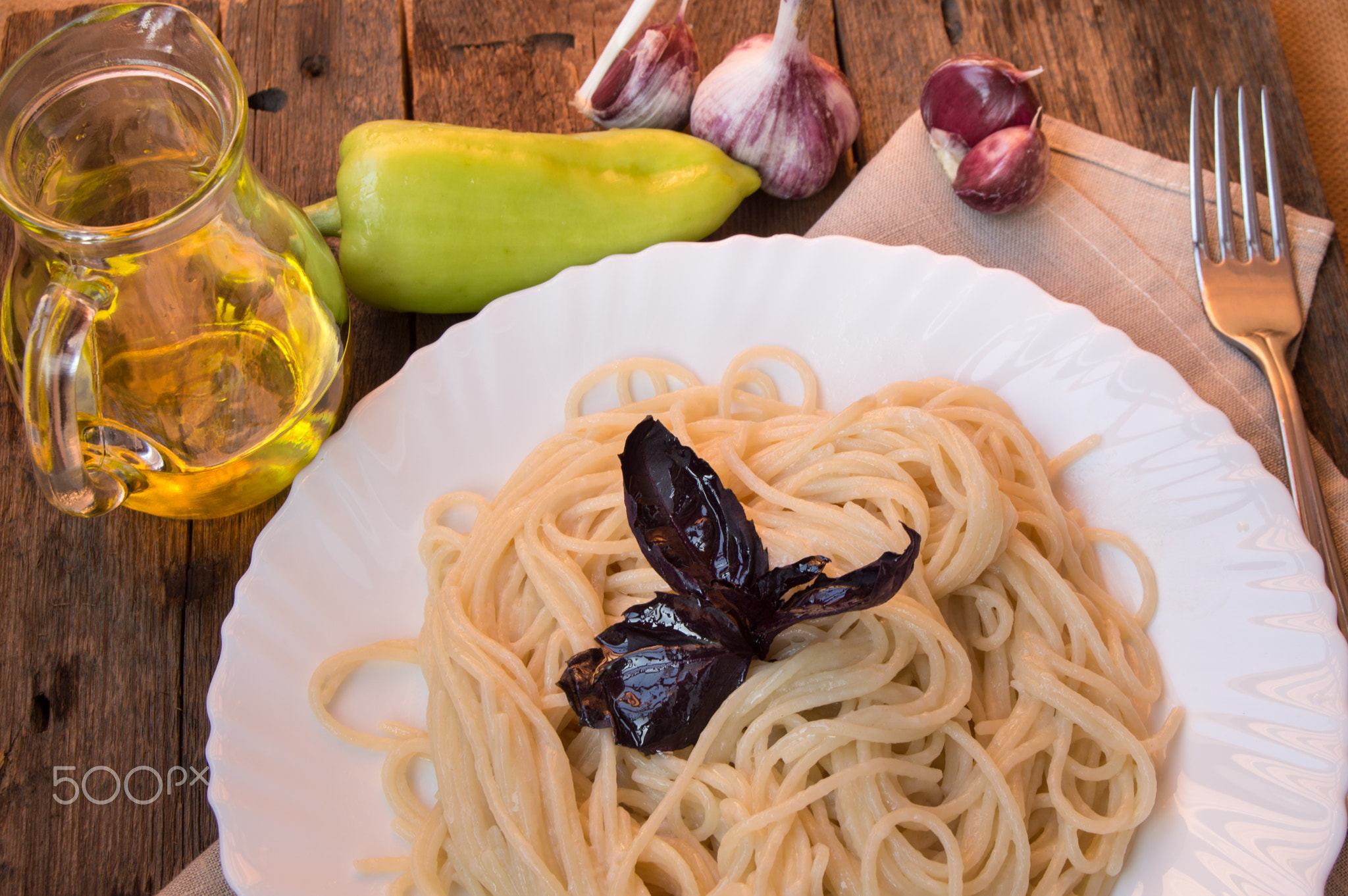 spaghetti pasta in a white plate with Basil on an old wooden table