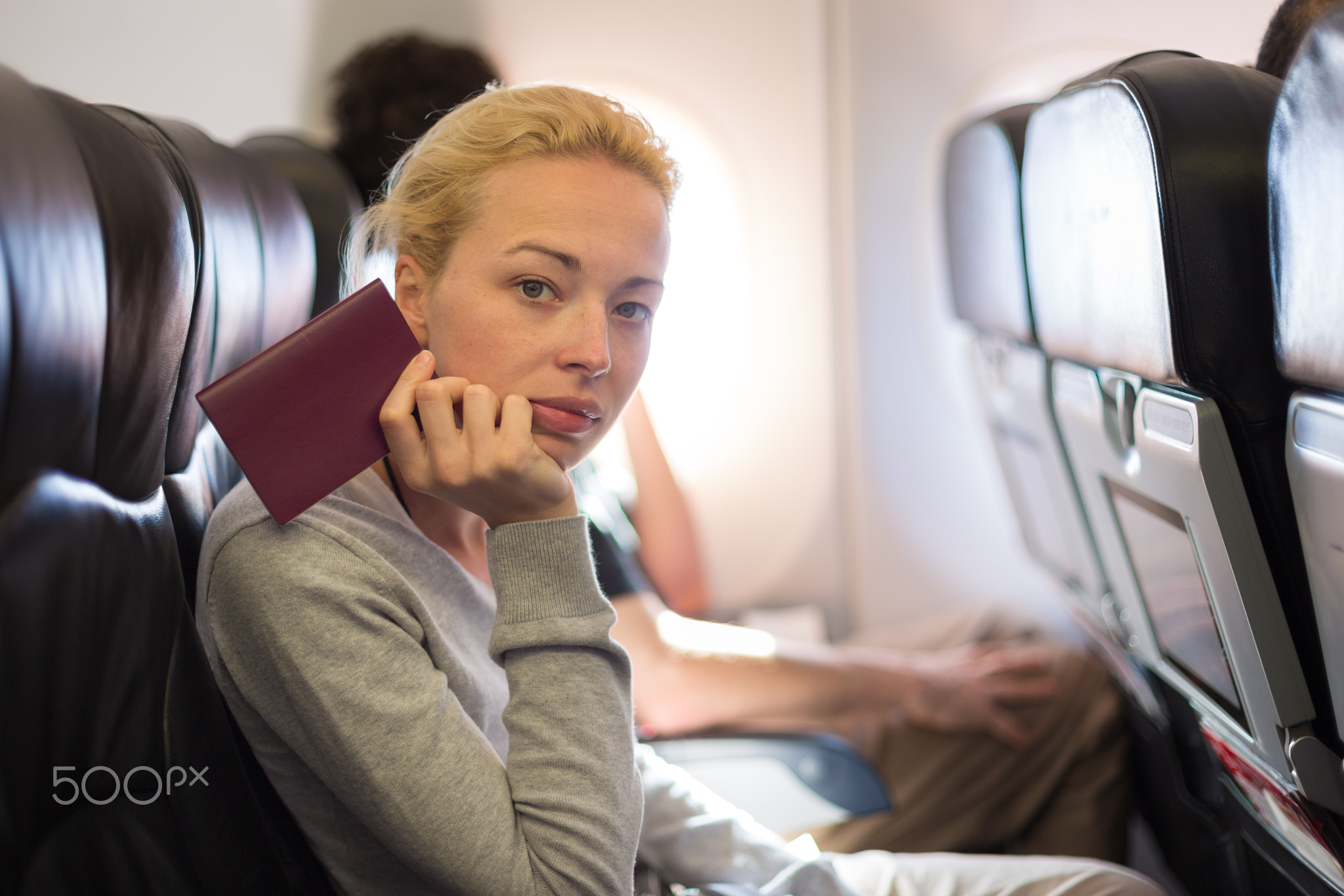 Woman traveling by plae holding passport in her hand.