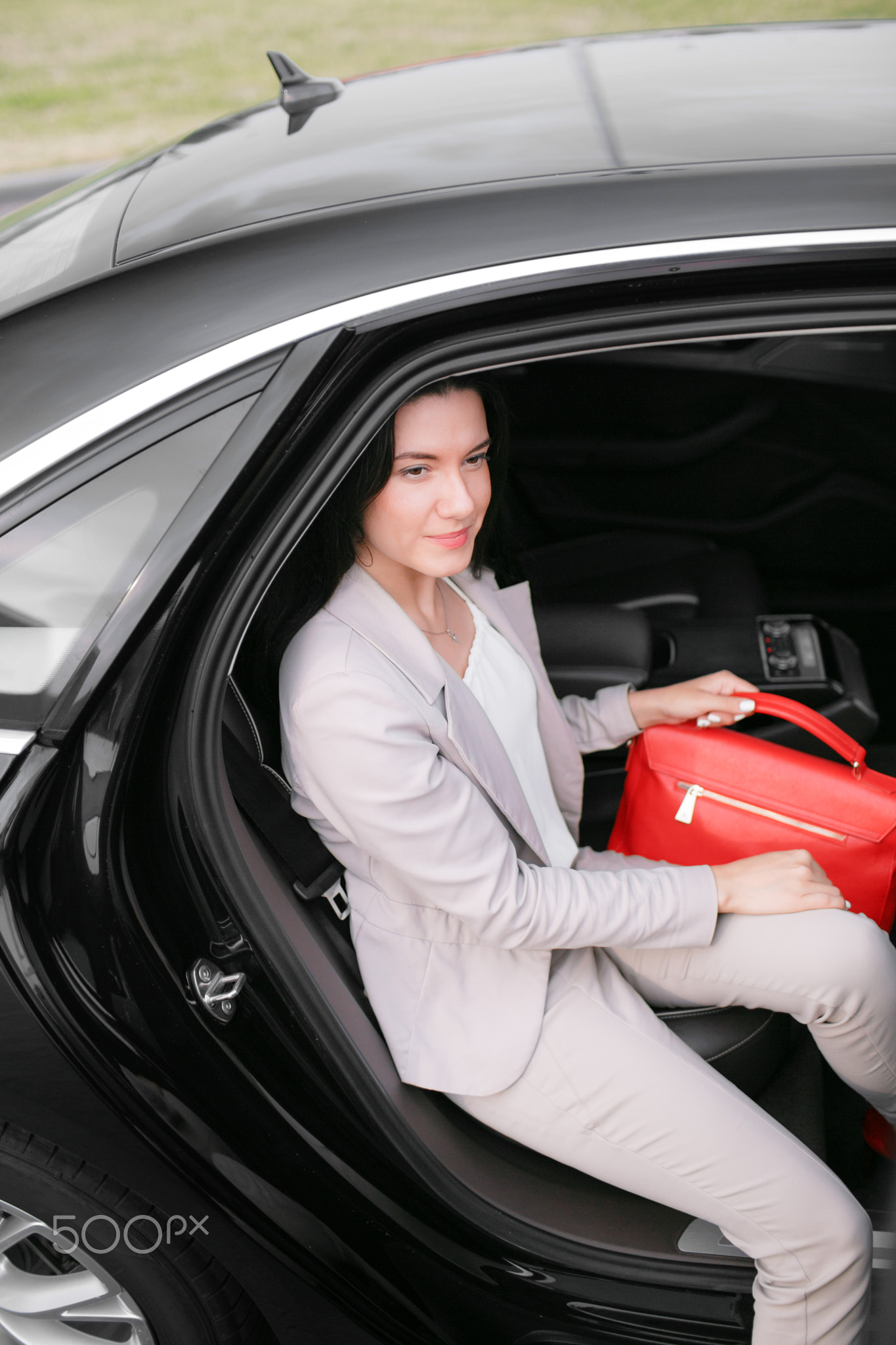 One Successful business woman. Young lady sitting on a backseat of luxury car