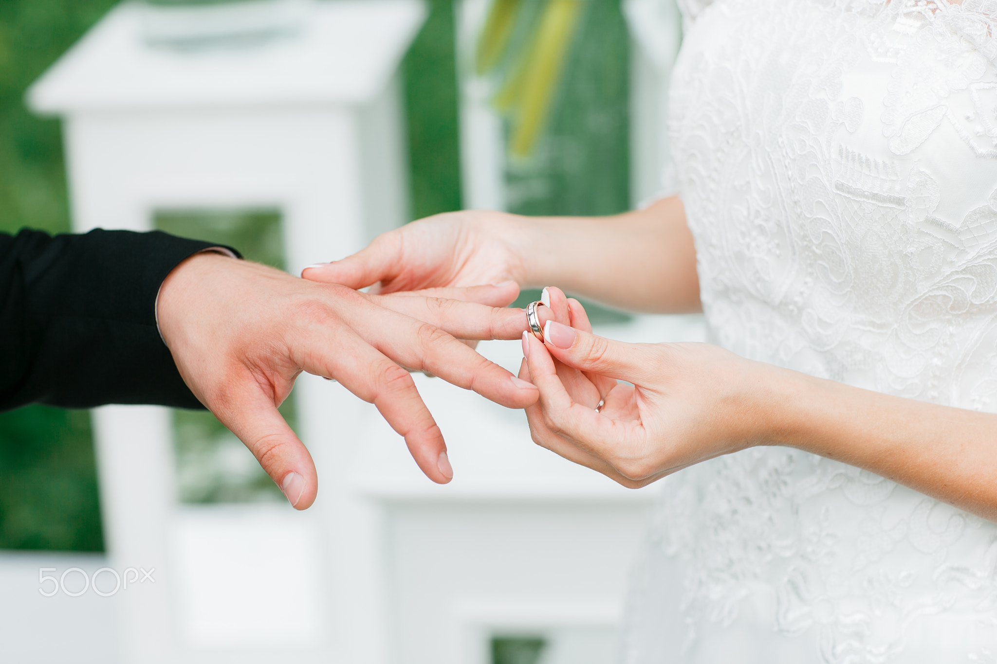 Close-up of a bride putting  wedding ring on  groom