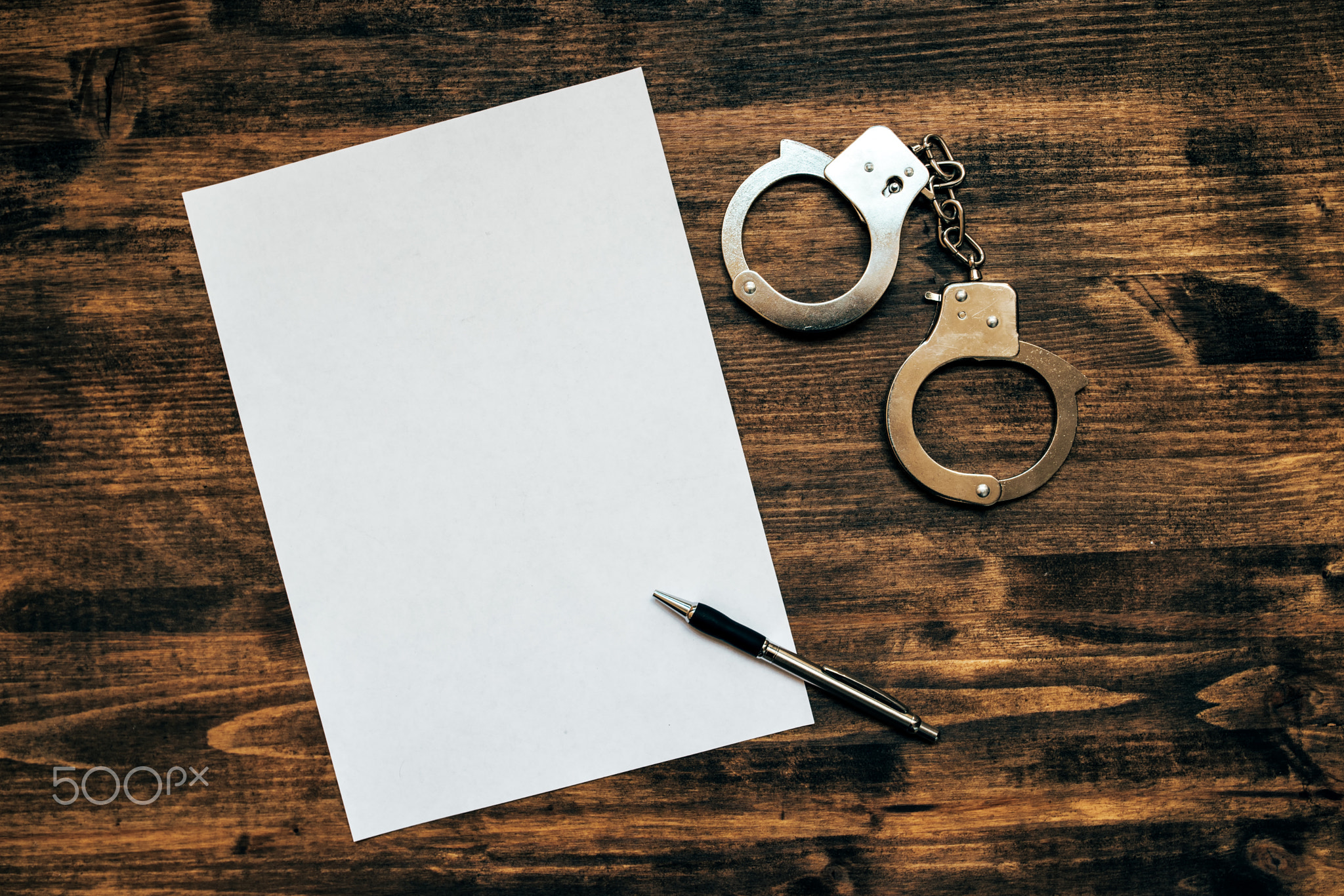 Police handcuffs and blank paper on investigator detective's wor