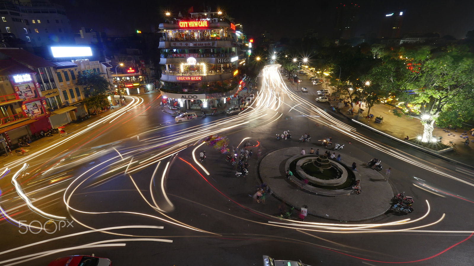 Panasonic Lumix DMC-GH4 + Olympus M.Zuiko Digital ED 7-14mm F2.8 PRO sample photo. City square with traffic in motion at night. hanoi, vietnam photography