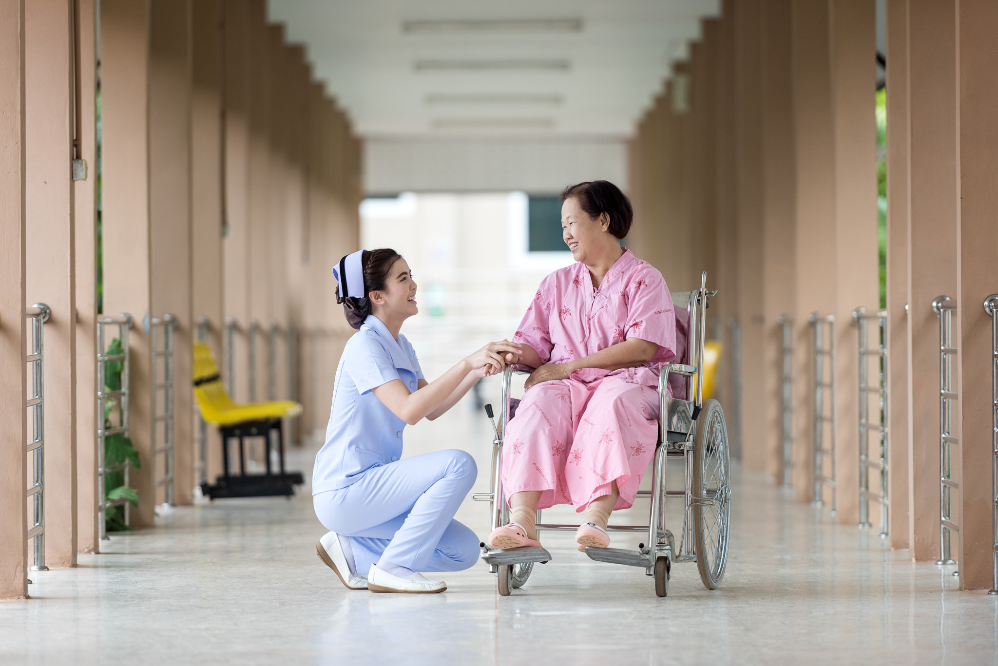 Senior woman in wheelchair talking to a nurse in a hospital