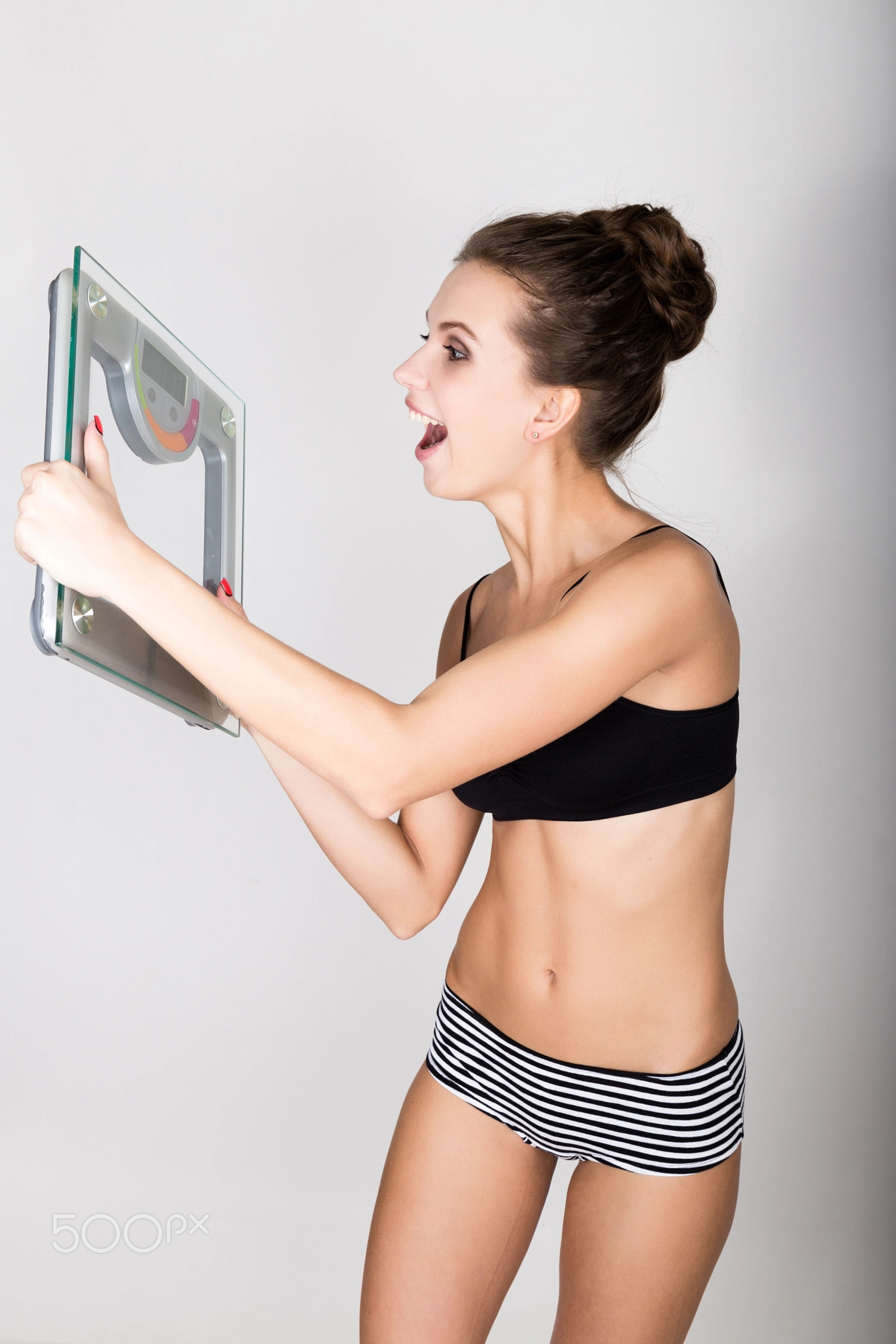 young sports woman holding scales and screaming on them