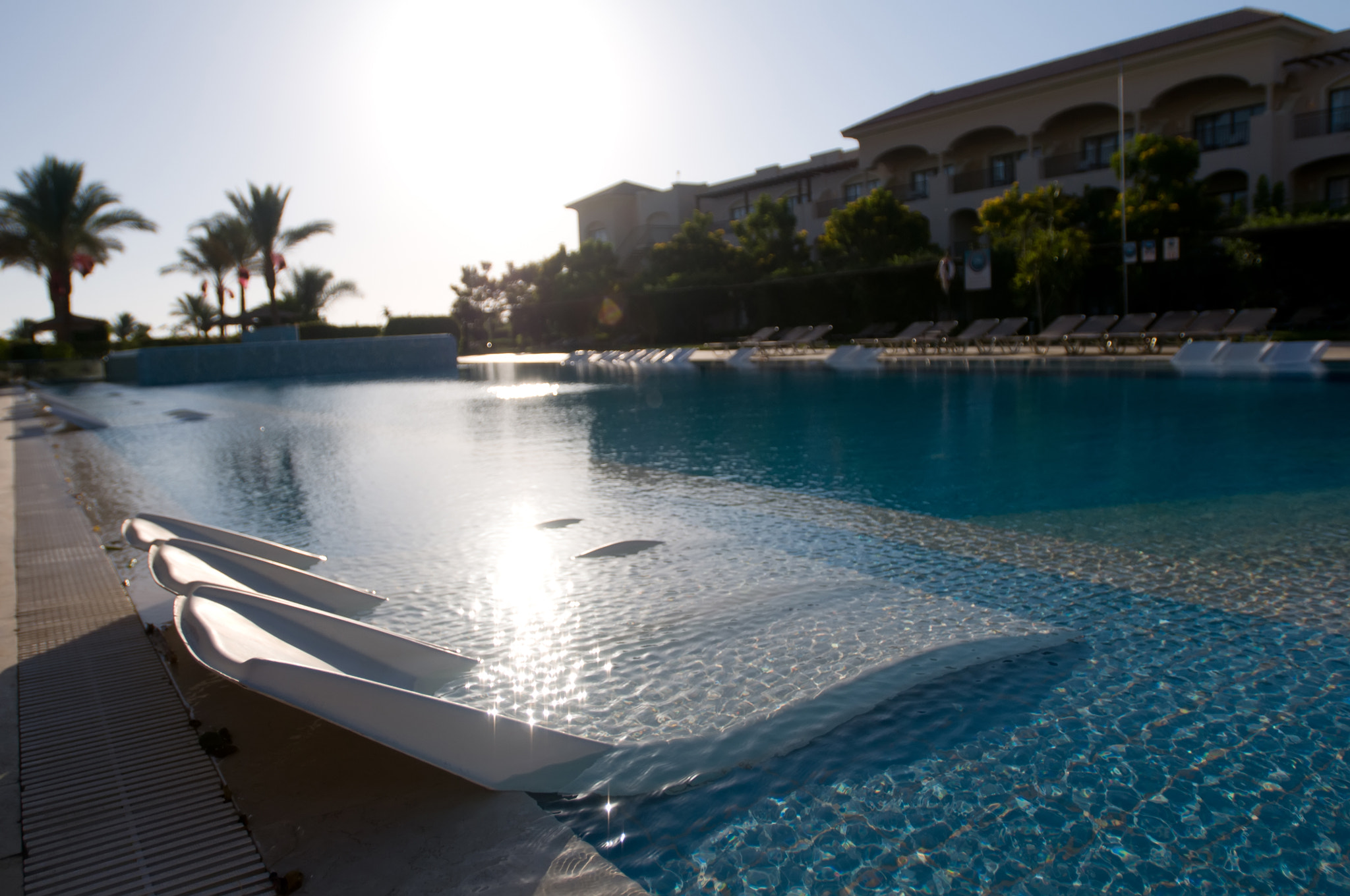 Nikon AF-S Nikkor 17-35mm F2.8D ED-IF sample photo. Blue pool at dawn with sunbeds near it photography
