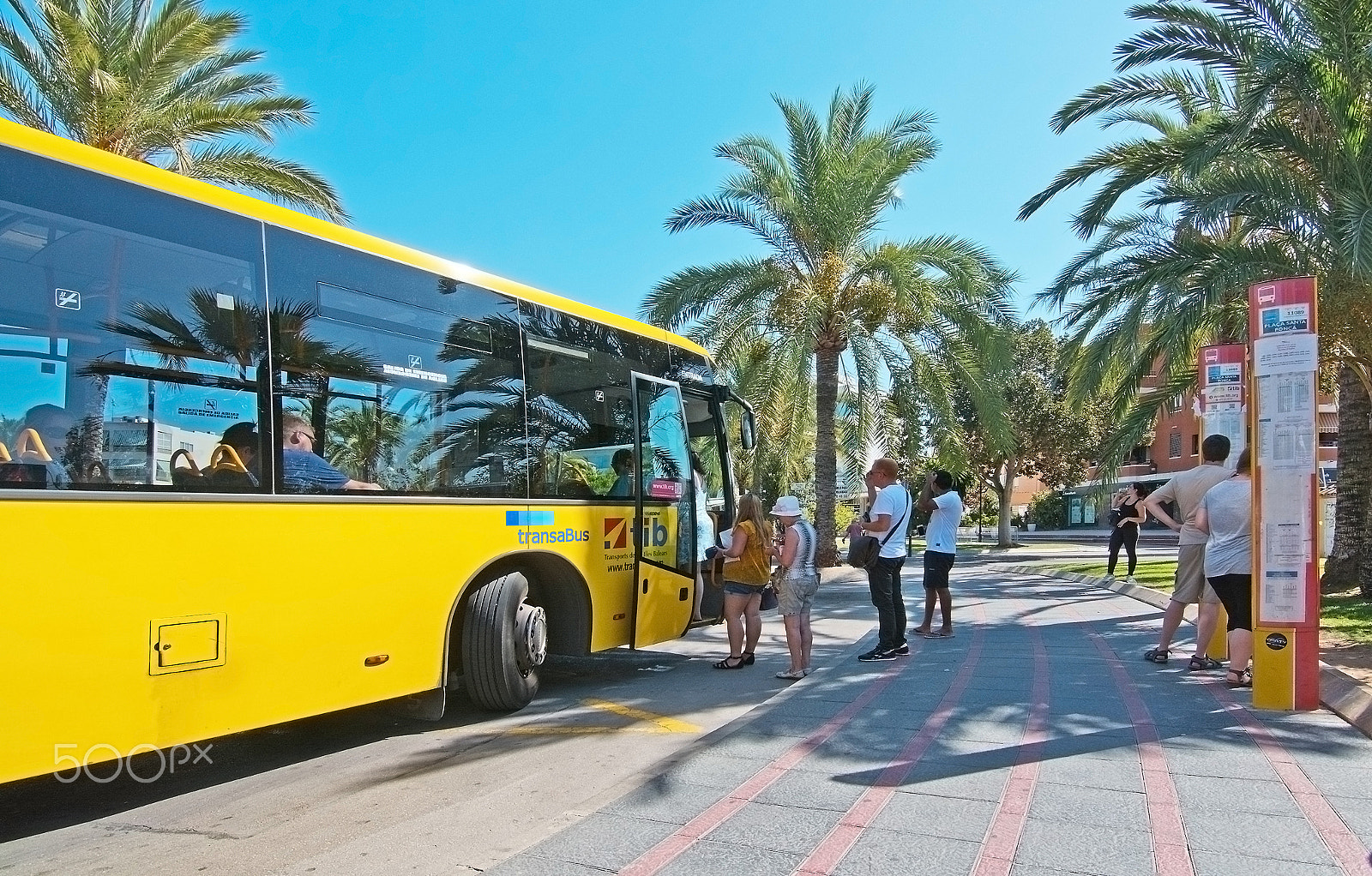 Nikon D7100 + Nikon AF-S Nikkor 500mm F4E FL ED VR sample photo. Passengers boarding a yellow regional bus photography