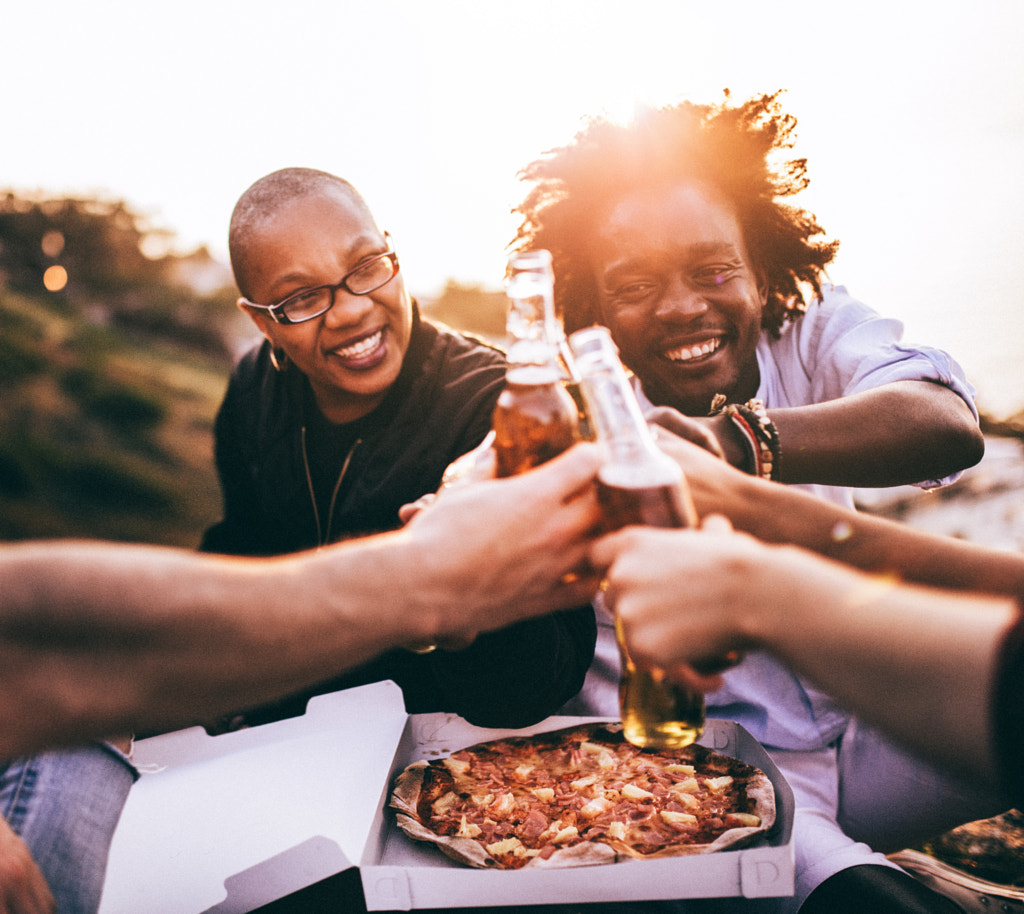 Friends celebrating with beer and pizza at picnic by Carina König on 500px.com