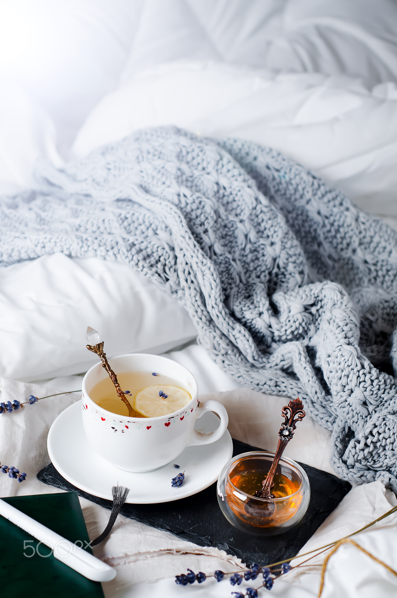 tray with honey and a cup of hot tea in the bed