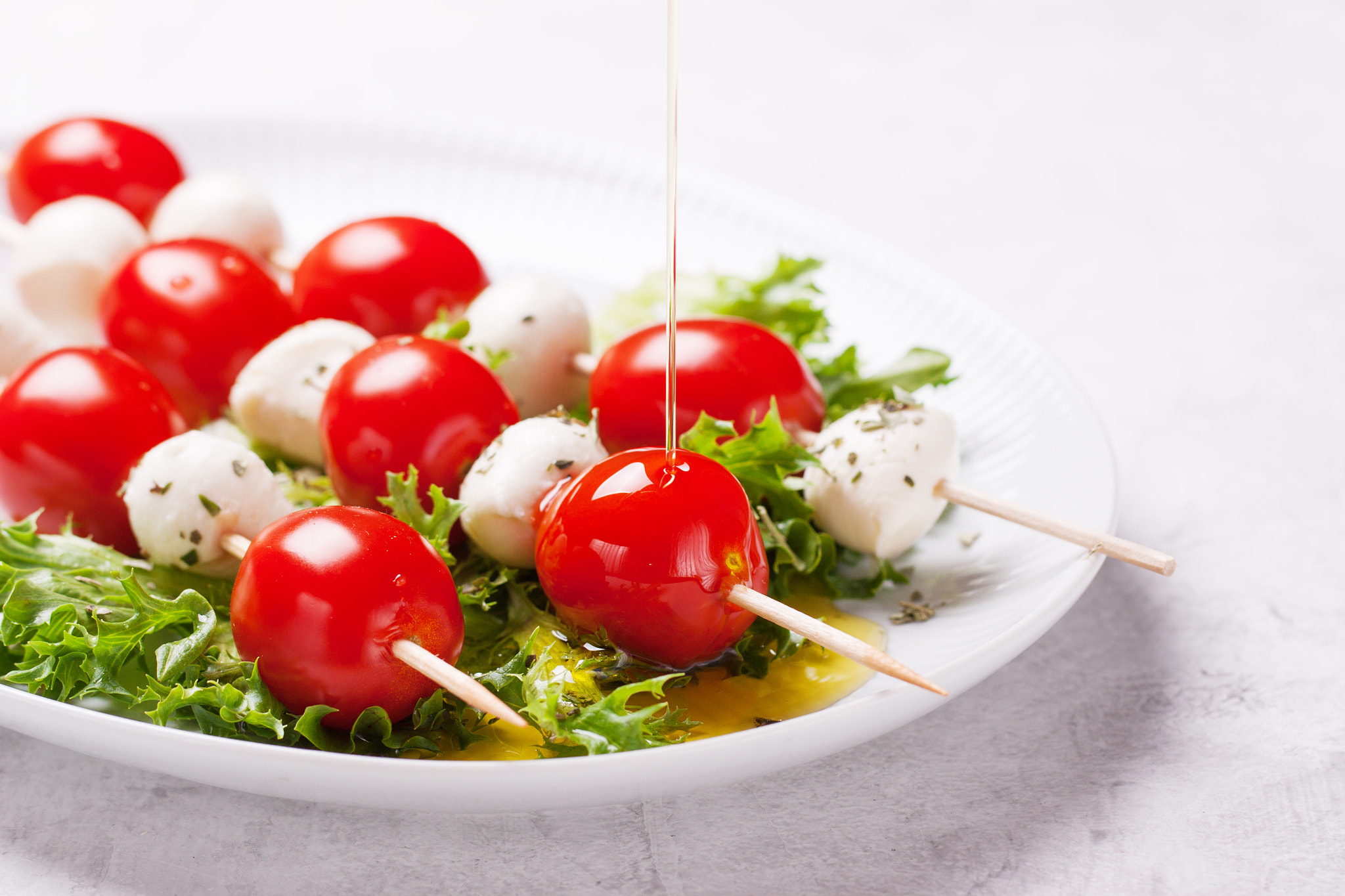 Tomatoes and mozzarella on sticks on salad leaves, closeup