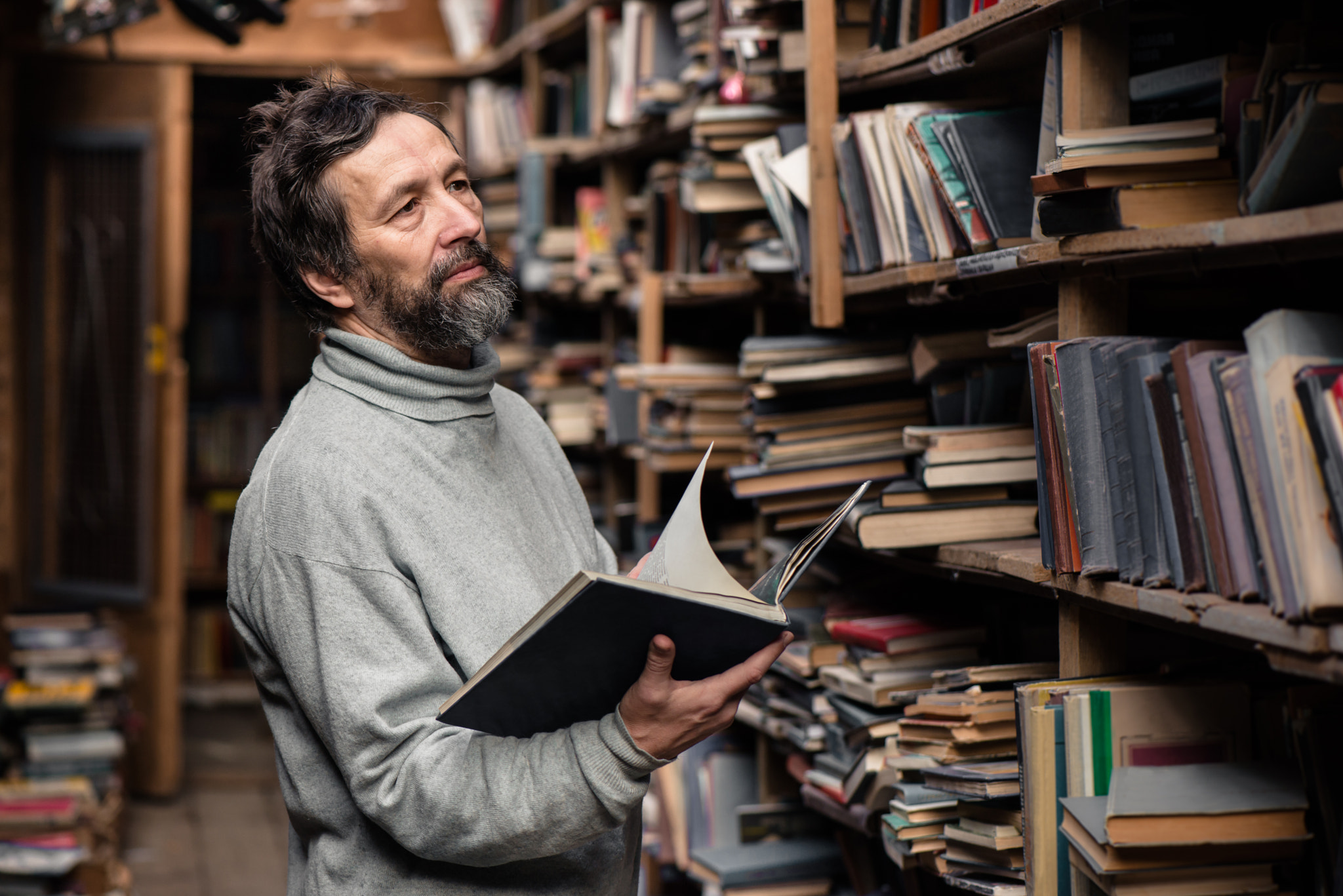 Authentic senior man reading book in the hand on book market