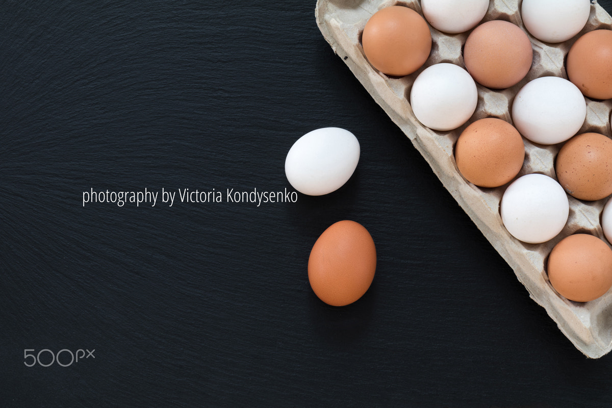 White and brown chicken eggs on black background