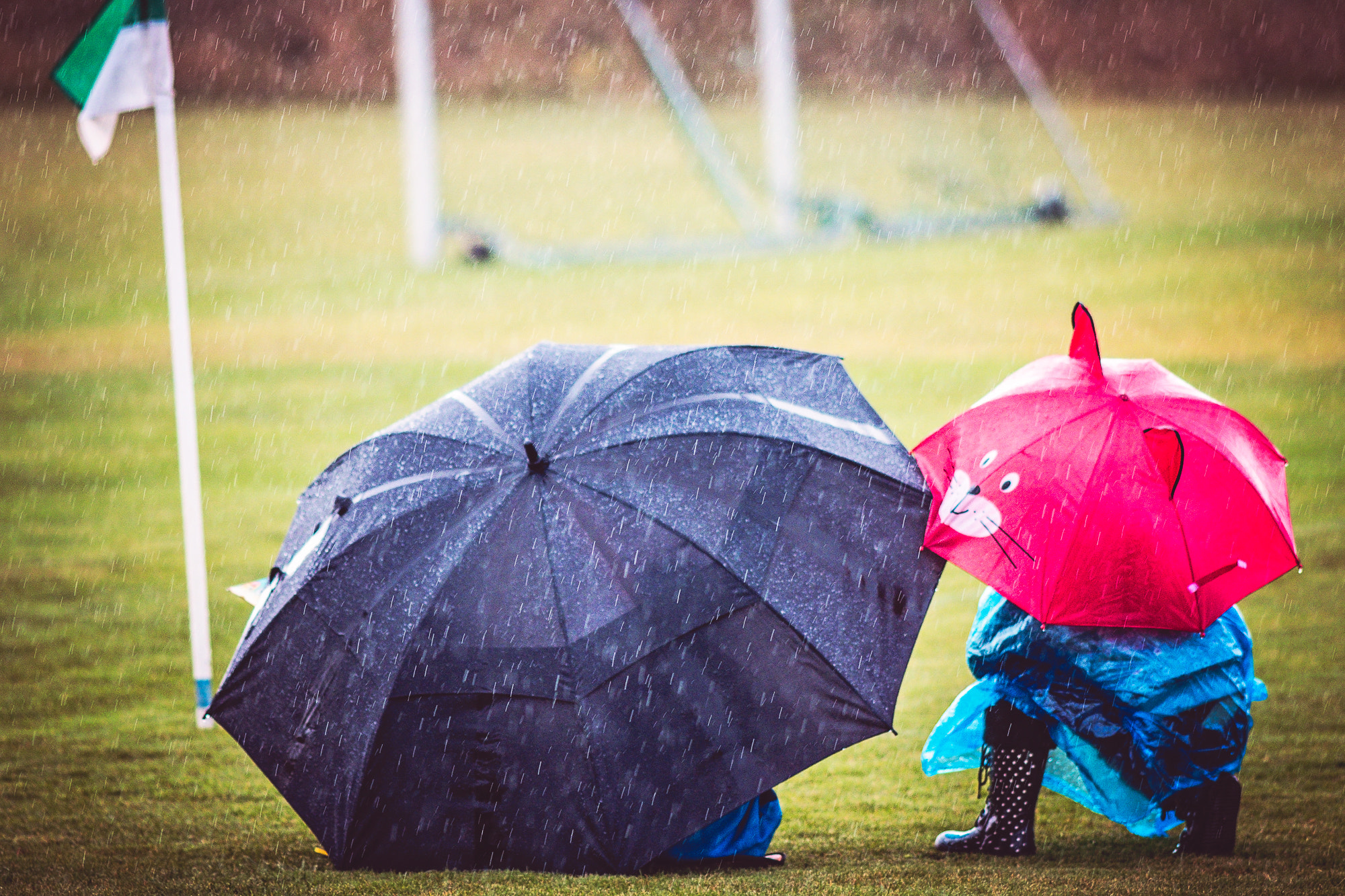 Canon EOS 80D + Canon EF 200mm F2.8L II USM sample photo. Little children hiding from the rain at the football game. photography
