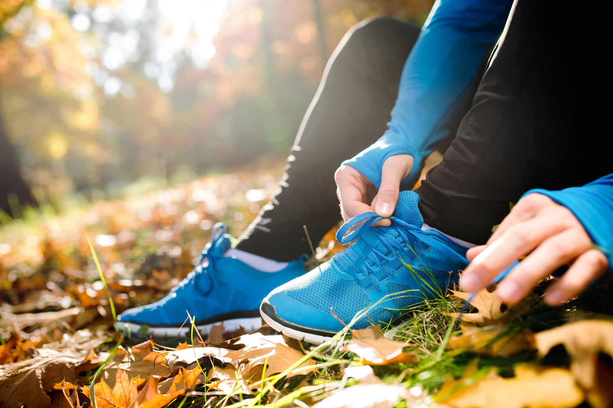 Nikon D4S sample photo. Unrecognizable runner sitting on the ground, tying shoelaces, au photography