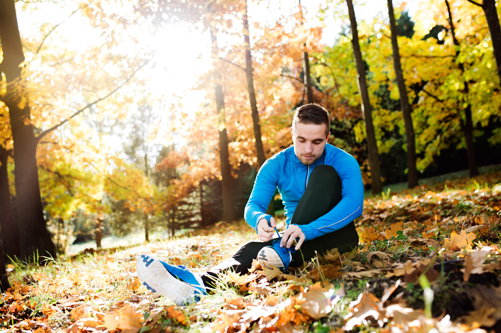 Nikon D4S sample photo. Runner sitting on the ground, tying shoelaces, autumn nature photography