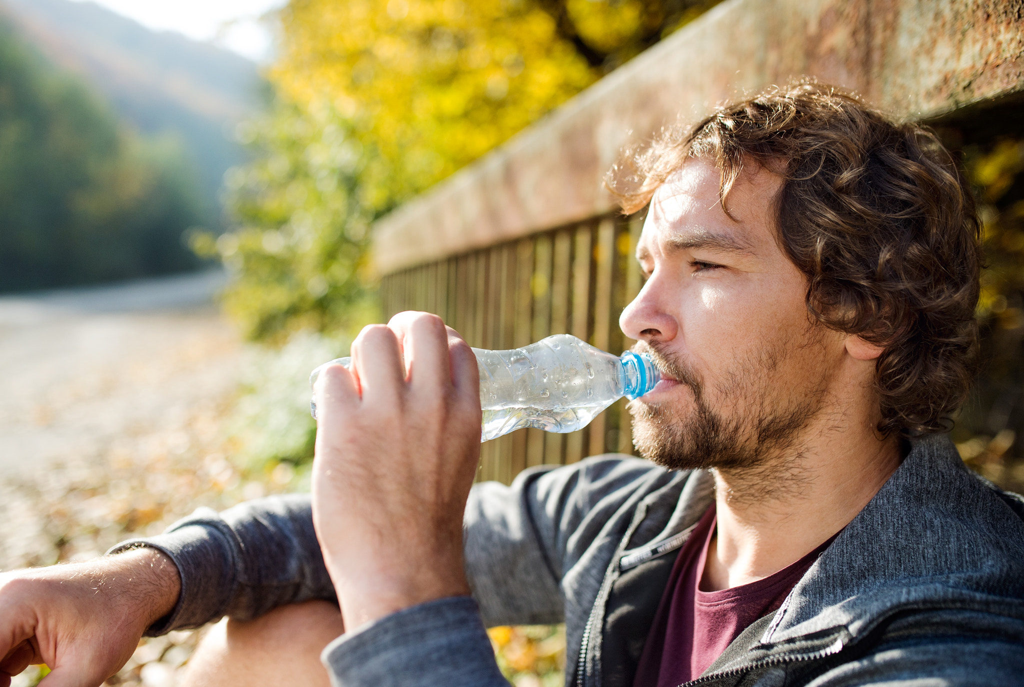 Nikon D4S sample photo. Young handsome runner with water bottle sitting on a bridge photography