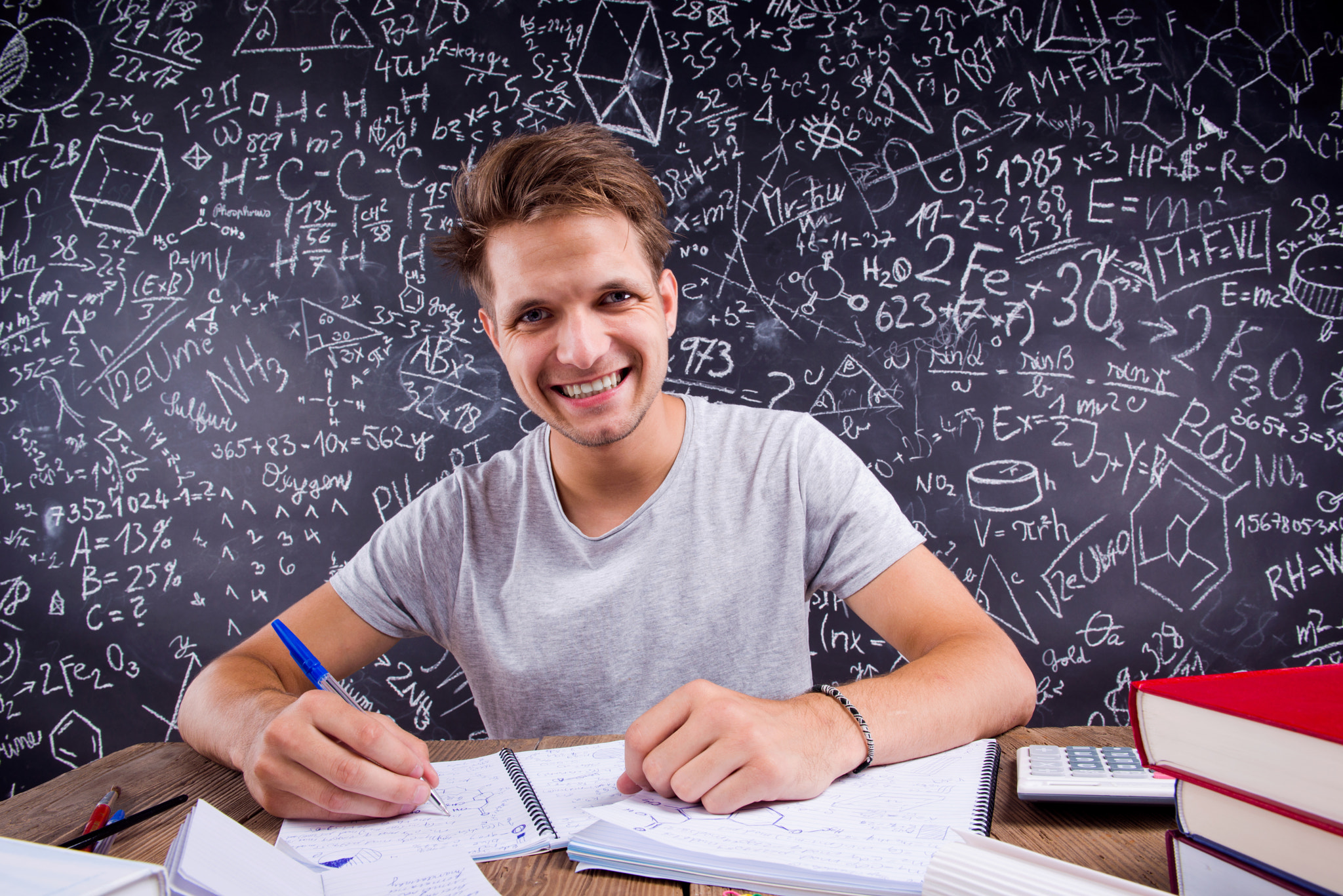Hipster student doing his homework against a big blackboard
