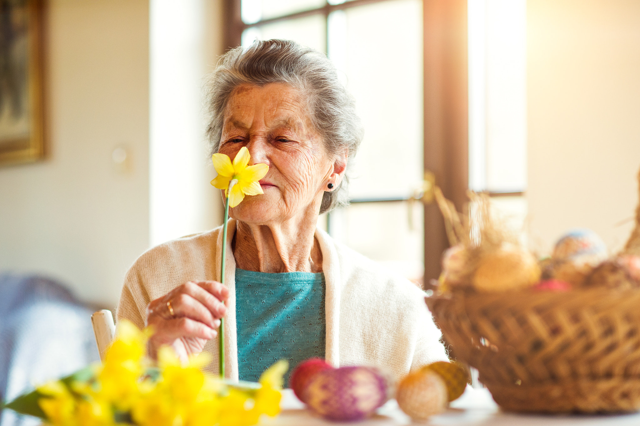 Nikon D4S sample photo. Senior woman by the window smelling yellow daffodil, easter photography