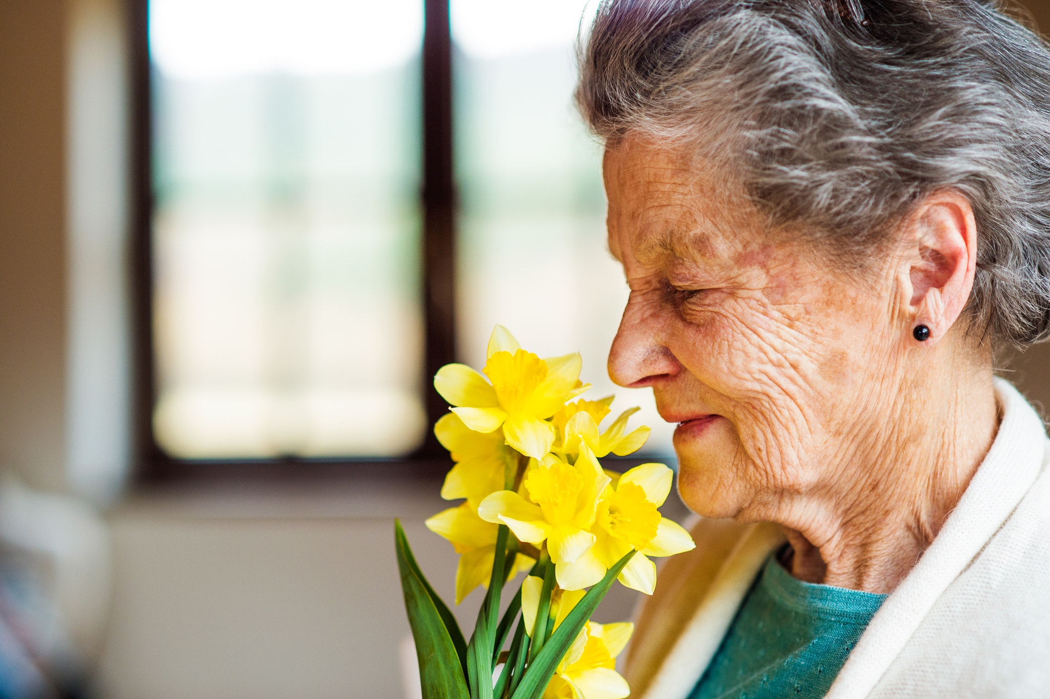 Nikon D4S sample photo. Senior woman by the window smelling bouquet of daffodils photography