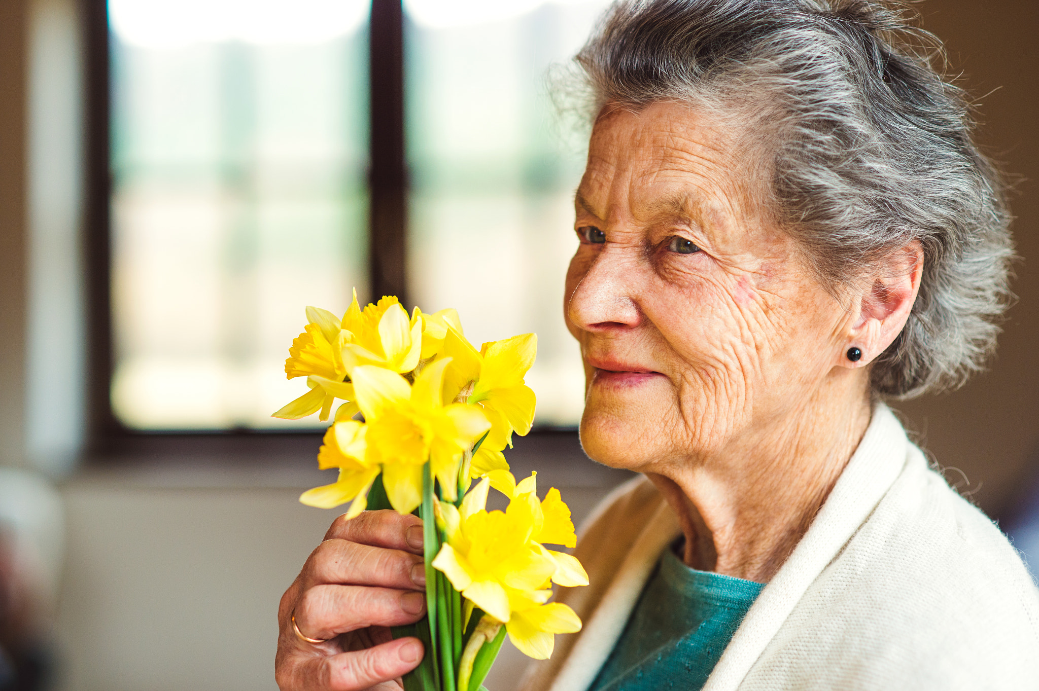 Nikon D4S + Nikon AF Nikkor 85mm F1.8D sample photo. Senior woman by the window holding bouquet of daffodils photography