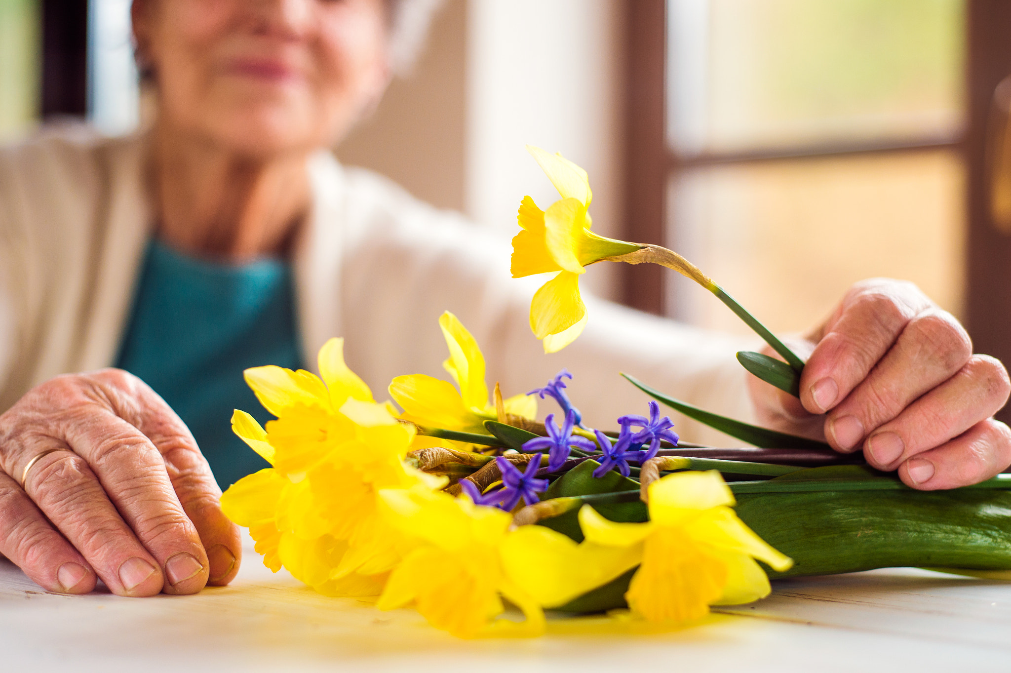 Nikon D4S + Nikon AF Nikkor 50mm F1.8D sample photo. Senior woman by the window holding bouquet of daffodils photography