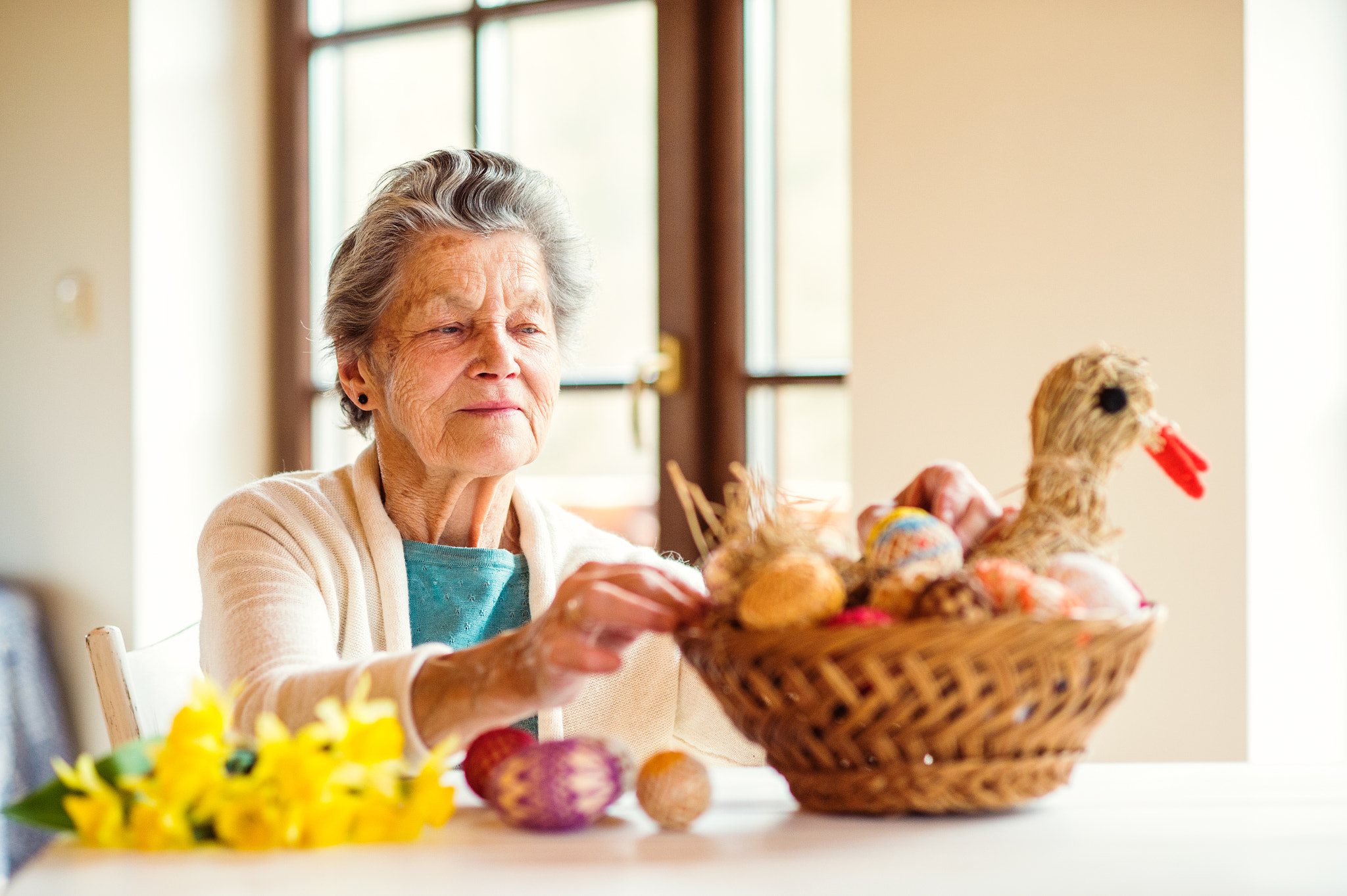 Nikon D4S + Nikon AF Nikkor 85mm F1.8D sample photo. Senior woman arranging basket with easter eggs and daffodils photography