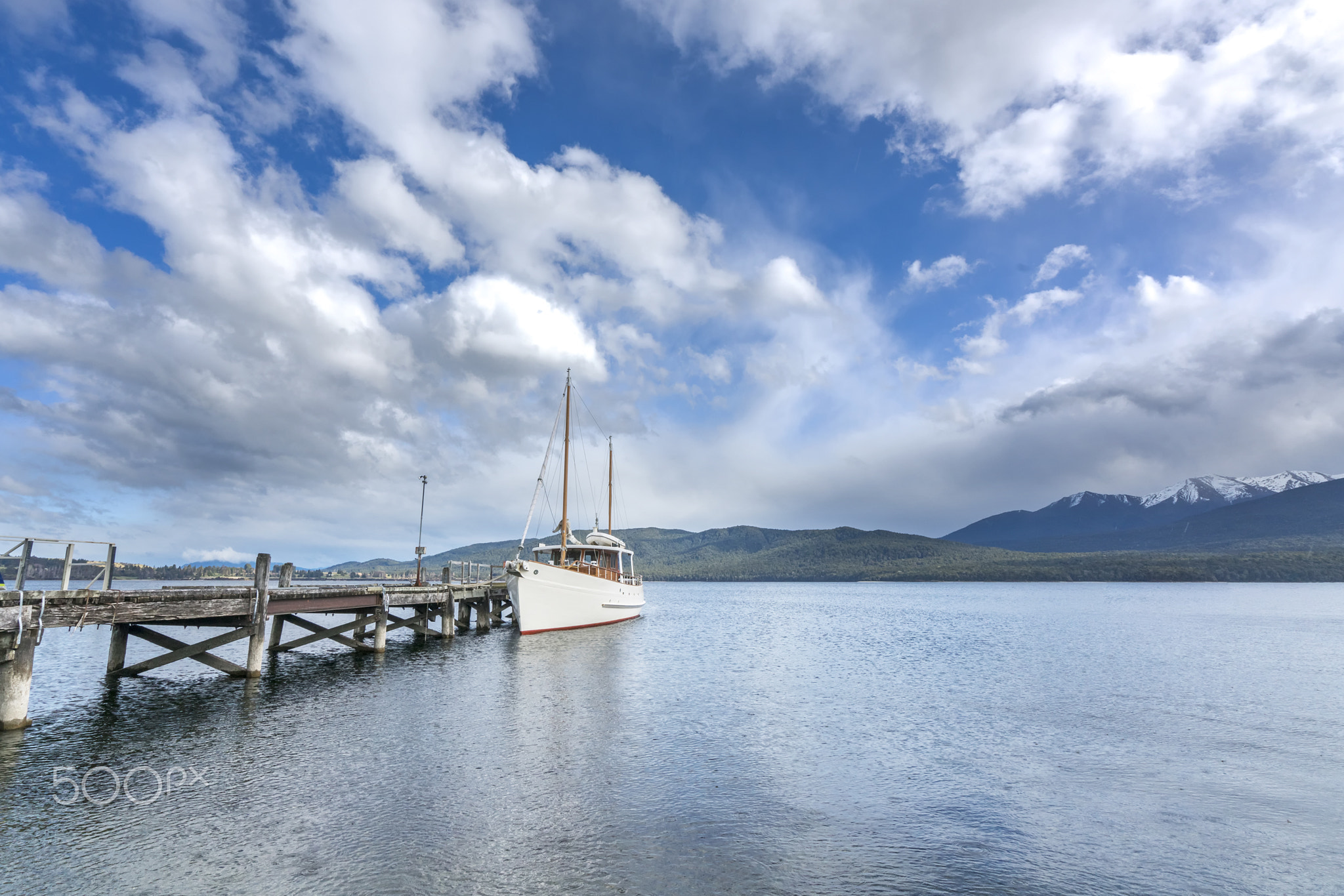 Ship park at wooden jetty with mountain background at Te Anau, New Zealand