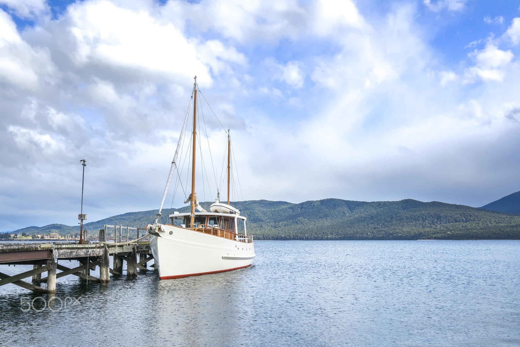 Ship park at wooden jetty with mountain background at Te Anau, New Zealand