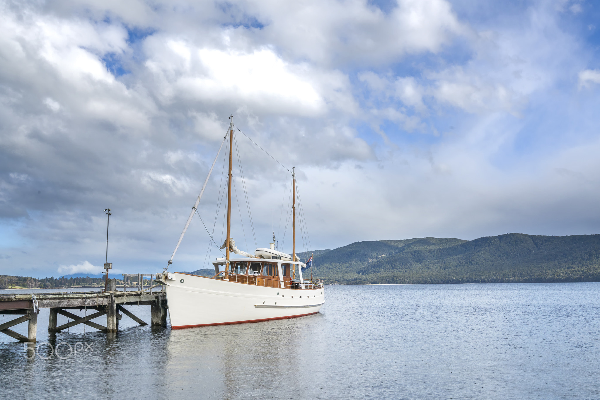 Ship park at wooden jetty with mountain background at Te Anau, New Zealand