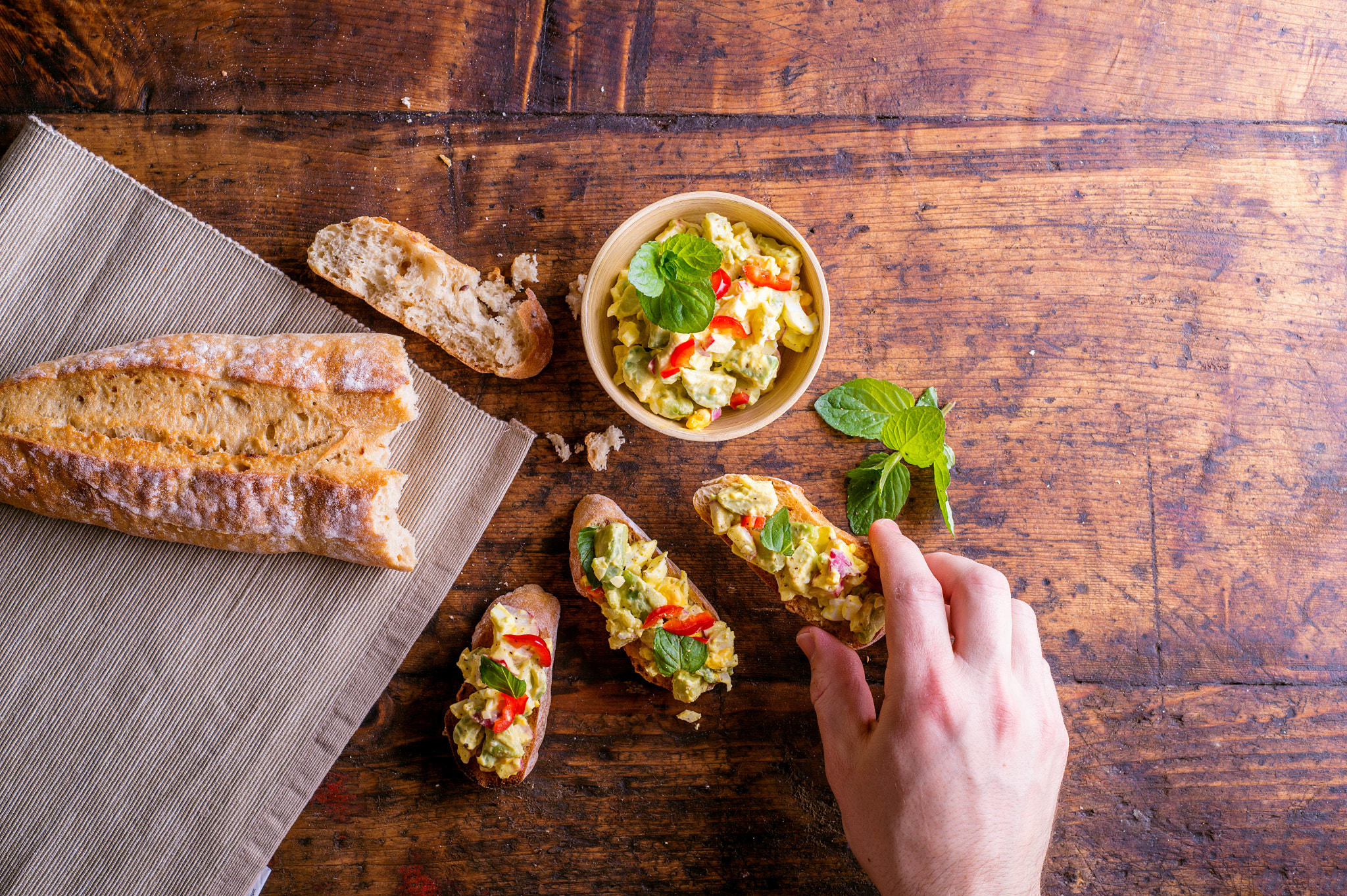 Nikon D4S sample photo. Man taking avocado spread on bruschetta slices, wooden table photography