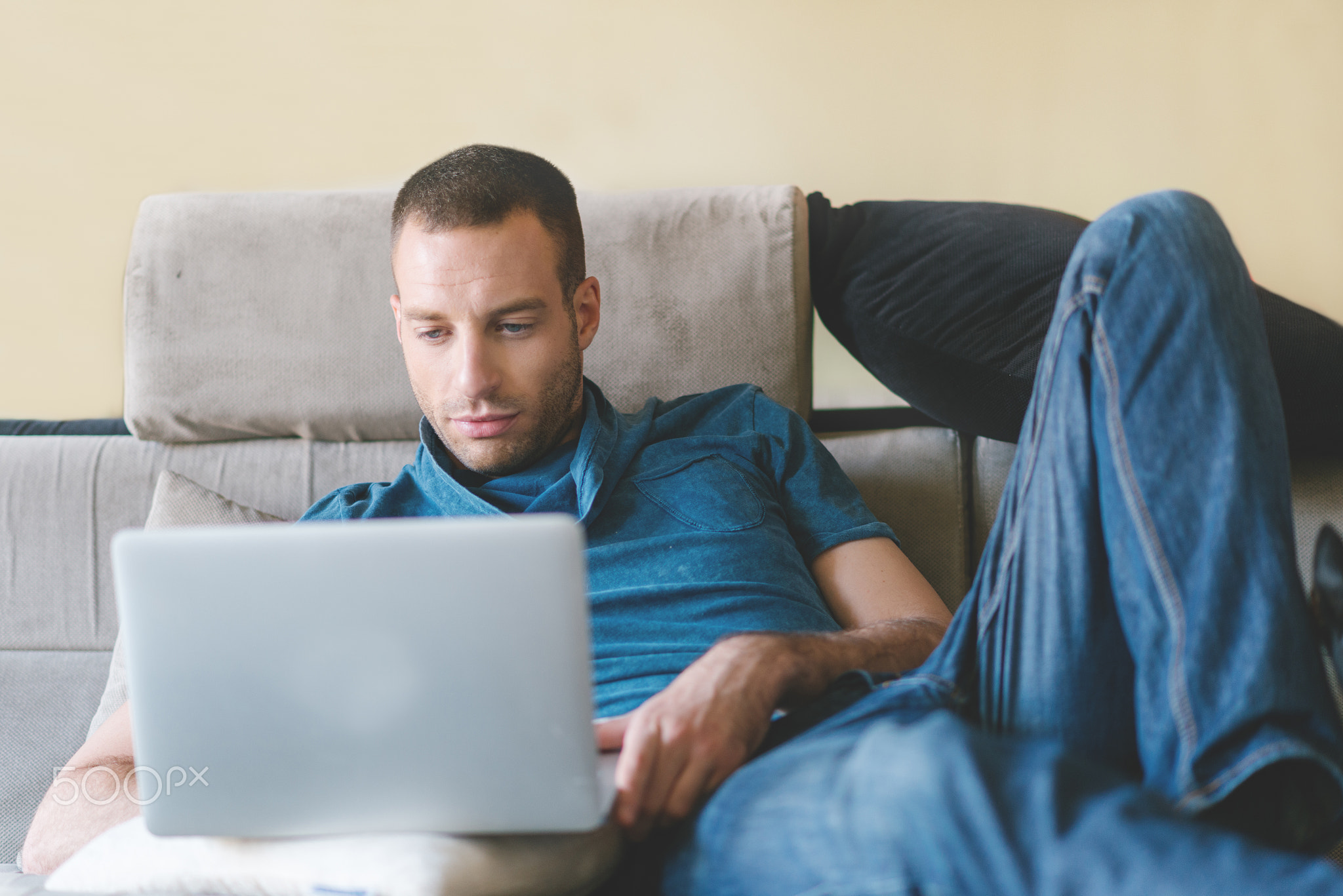 Young smiling man working at home and using laptop