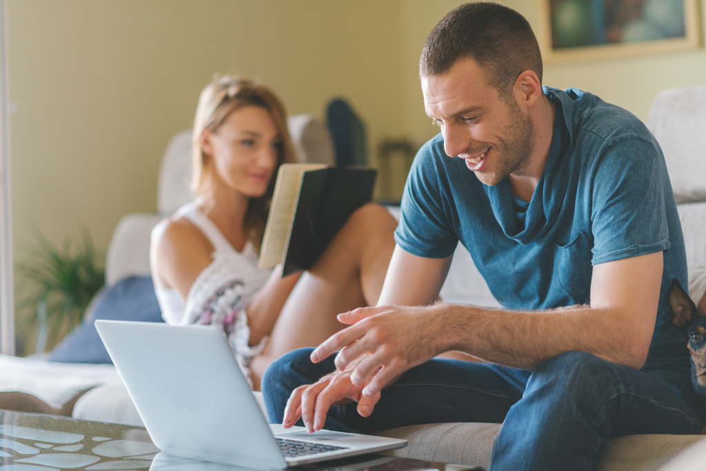 Young smiling couple working at home by Igor Milic on 500px.com