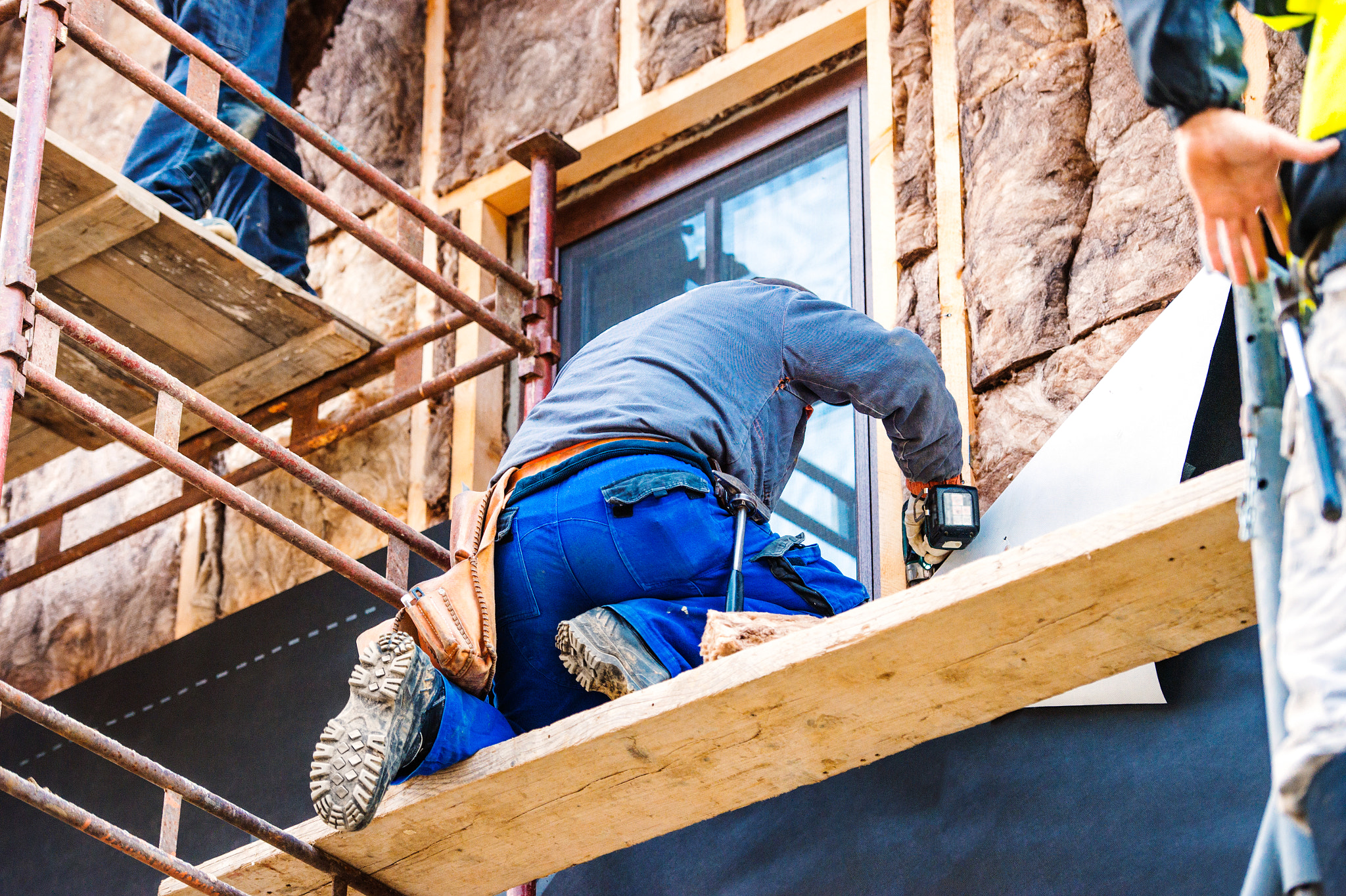 Construction workers thermally insulating house facade with glas
