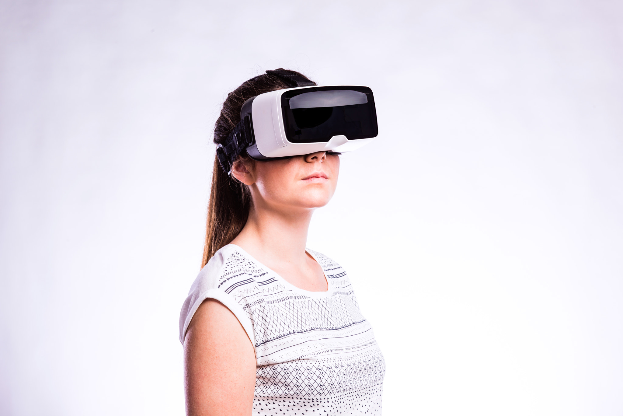 Woman with virtual reality goggles. Studio shot, gray background