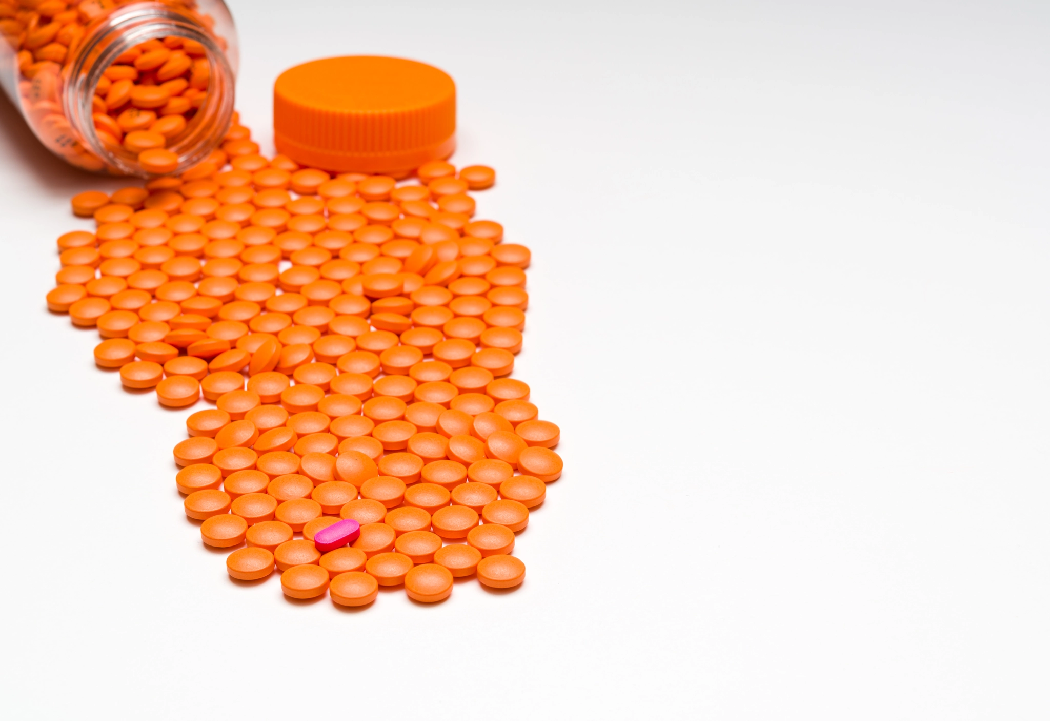 Medication, pills spilling out onto a white surface. With room f
