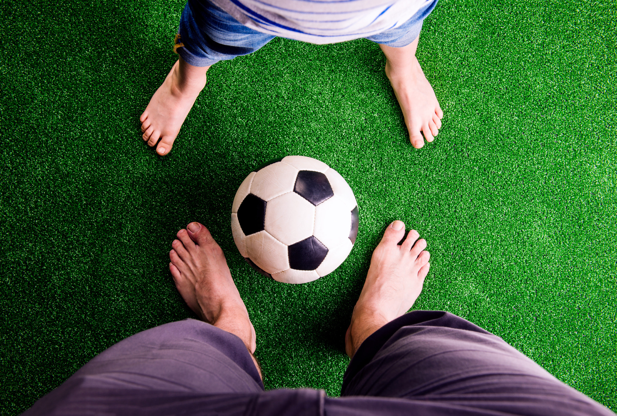 Father and son with soccer ball against green grass