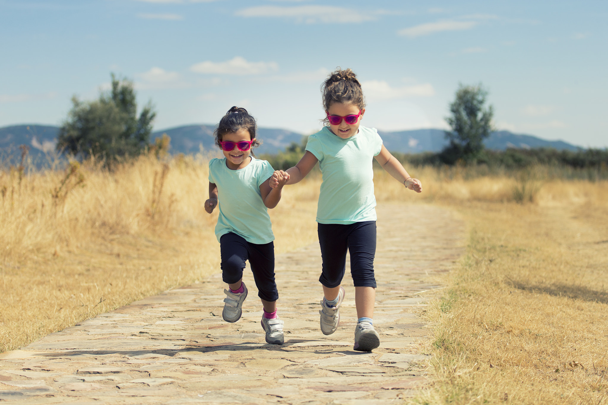 Canon EF 100-400mm F4.5-5.6L IS USM sample photo. Lovely twins jumping along path in countryside photography
