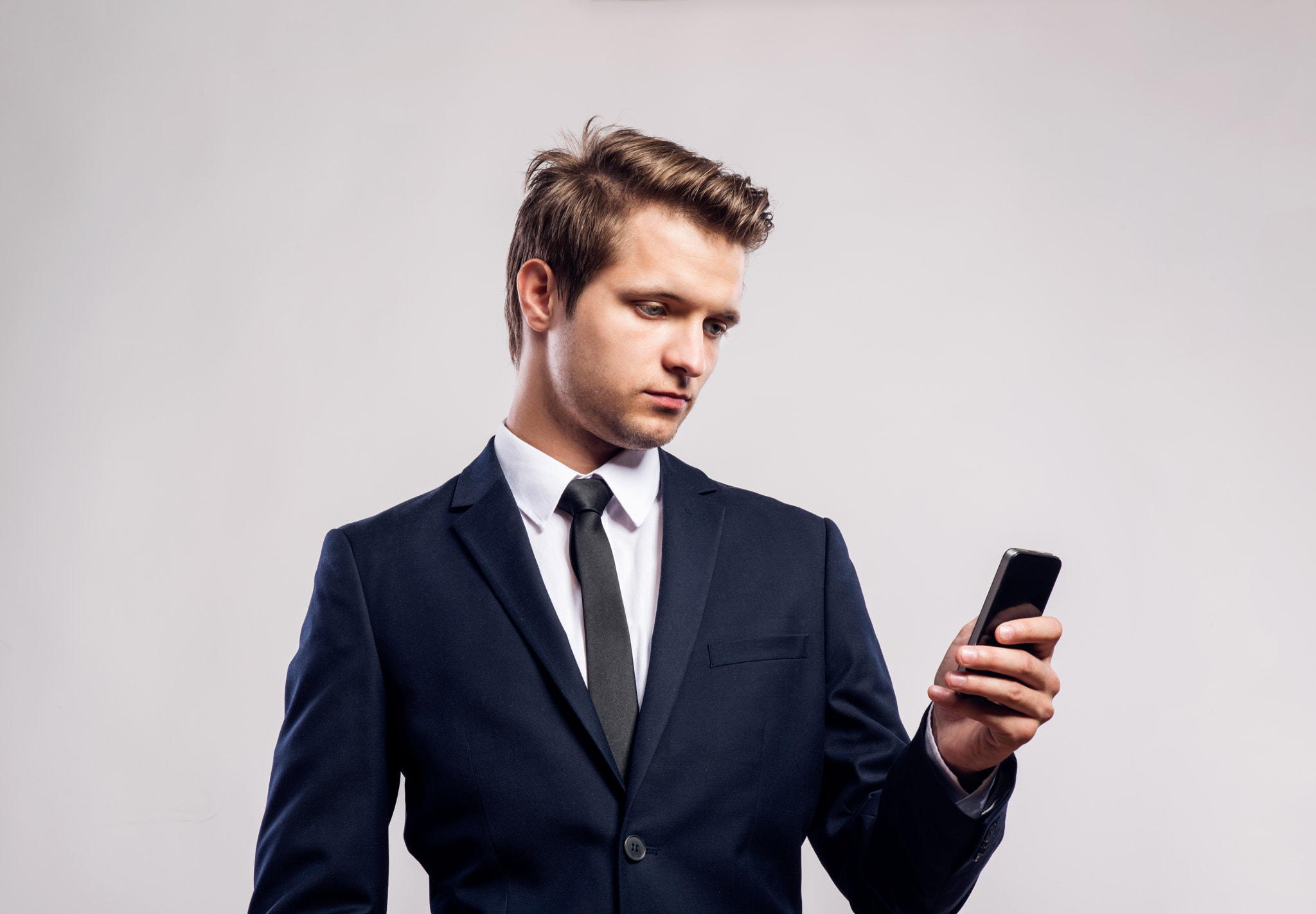 Hipster businessman with smartphone writing text message. Studio