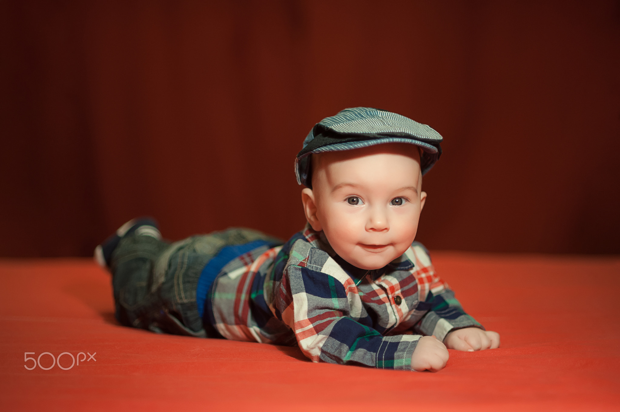 baby in tweed flat cap with a red background