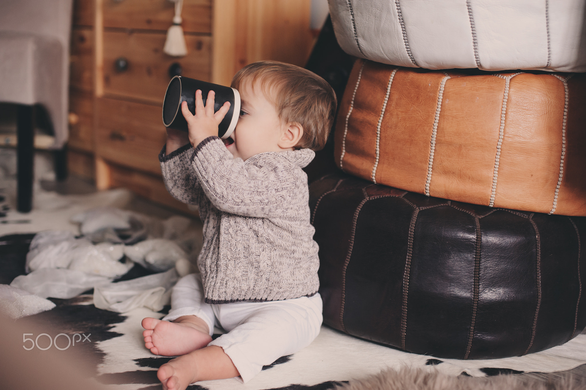 cute baby boy playing with cup at home, learning to drink, lifestyle capture in real life cozy...