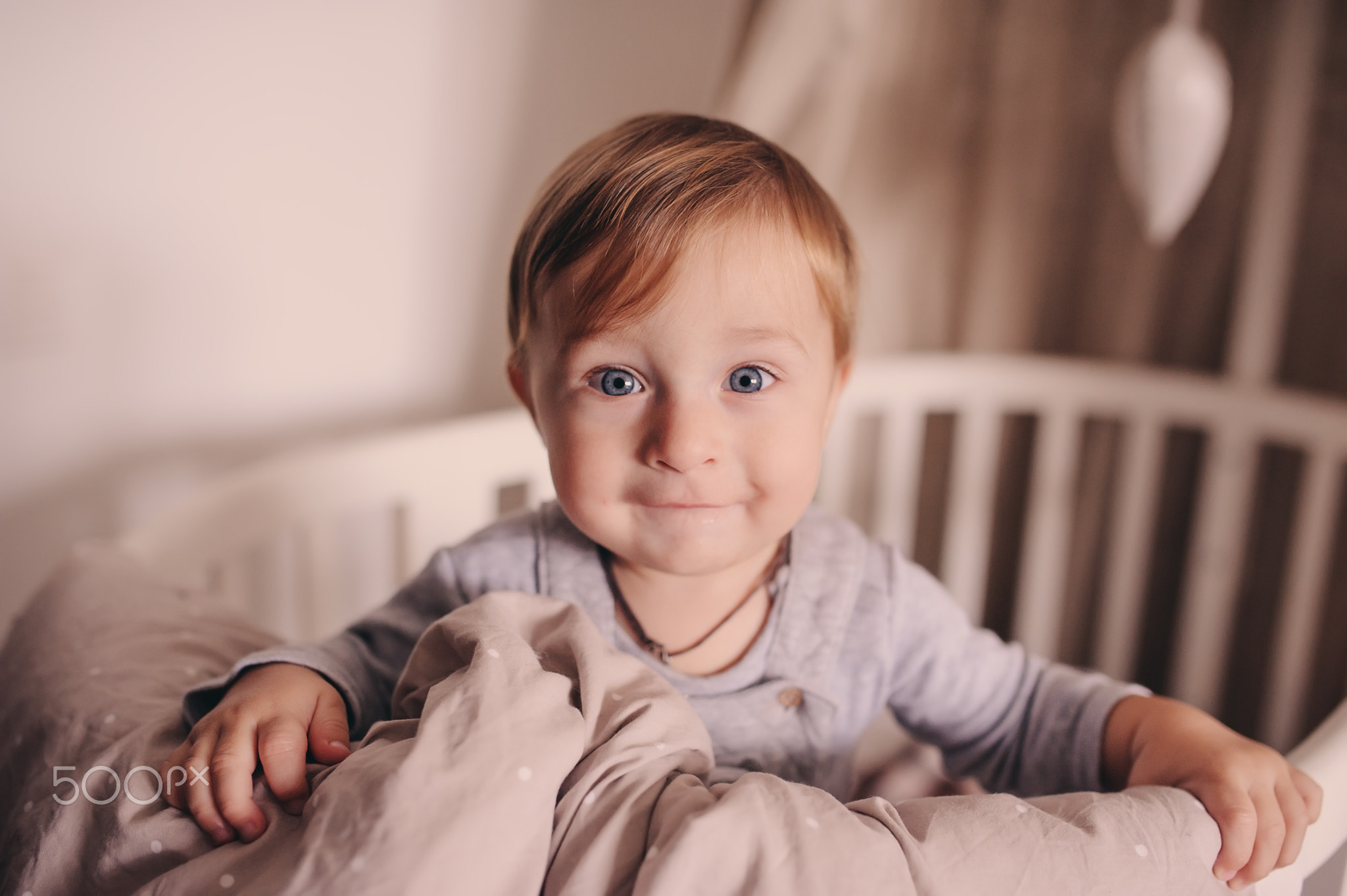 cute happy baby boy awake in his bed in the morning and playing. Candid capture in real life...