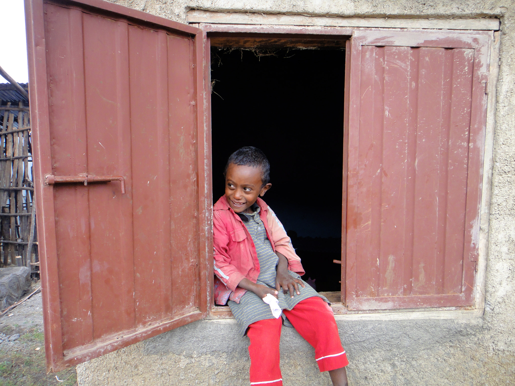 Sony DSC-TX7 sample photo. Ethiopia, dessie, mud hut, window, boy, little boy, mismatched clothes, smiling, looking away,... photography