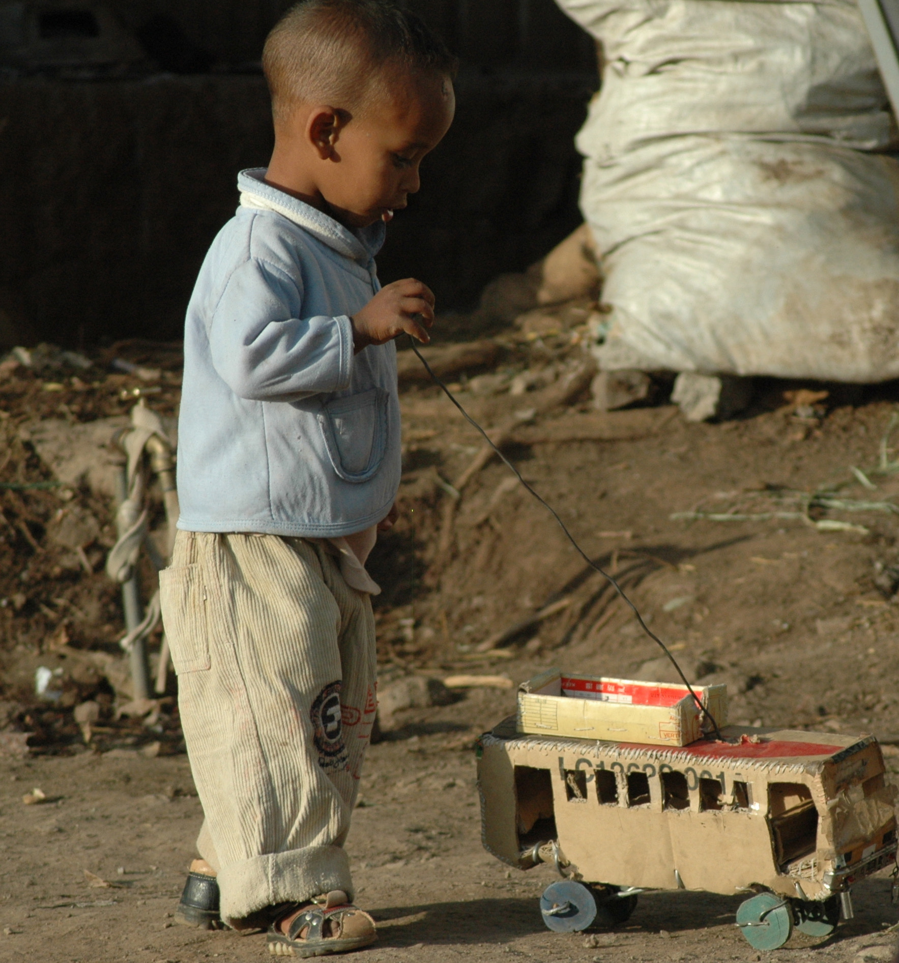 Nikon D70s + Tamron AF 70-300mm F4-5.6 Di LD Macro sample photo. Ethiopia, village boy, little boy, baggy pants, playing, toy train, dirt road, child, blue shirt,... photography