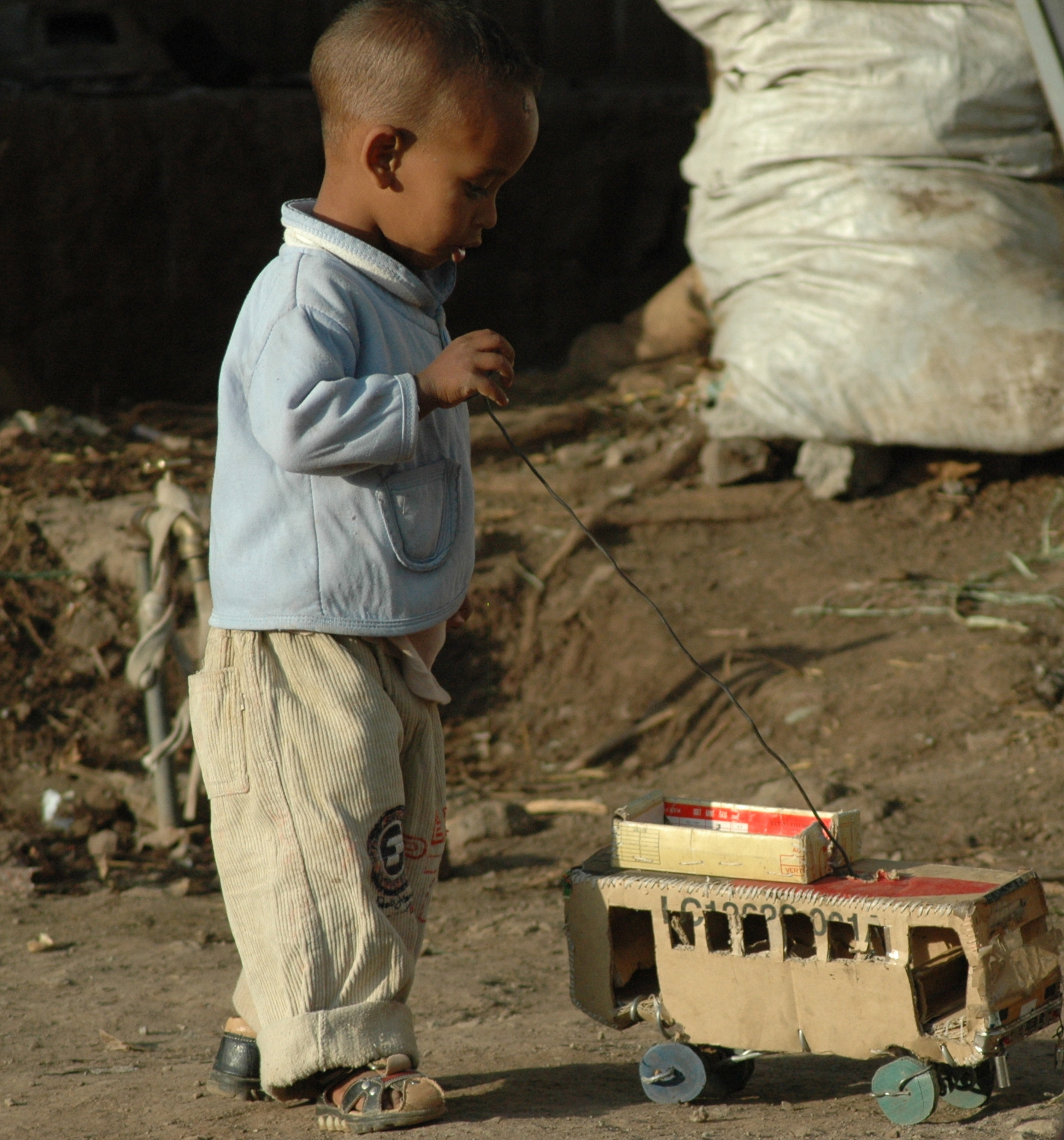 Nikon D70s sample photo. Ethiopia, village boy, little boy, baggy pants, playing, toy train, dirt road, child, blue shirt,... photography
