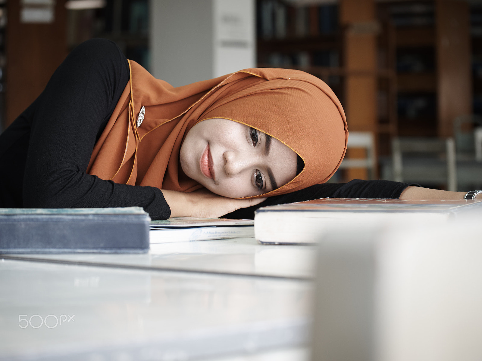 Olympus OM-D E-M1 + Panasonic Lumix G X Vario 35-100mm F2.8 OIS sample photo. Girl laying in library photography