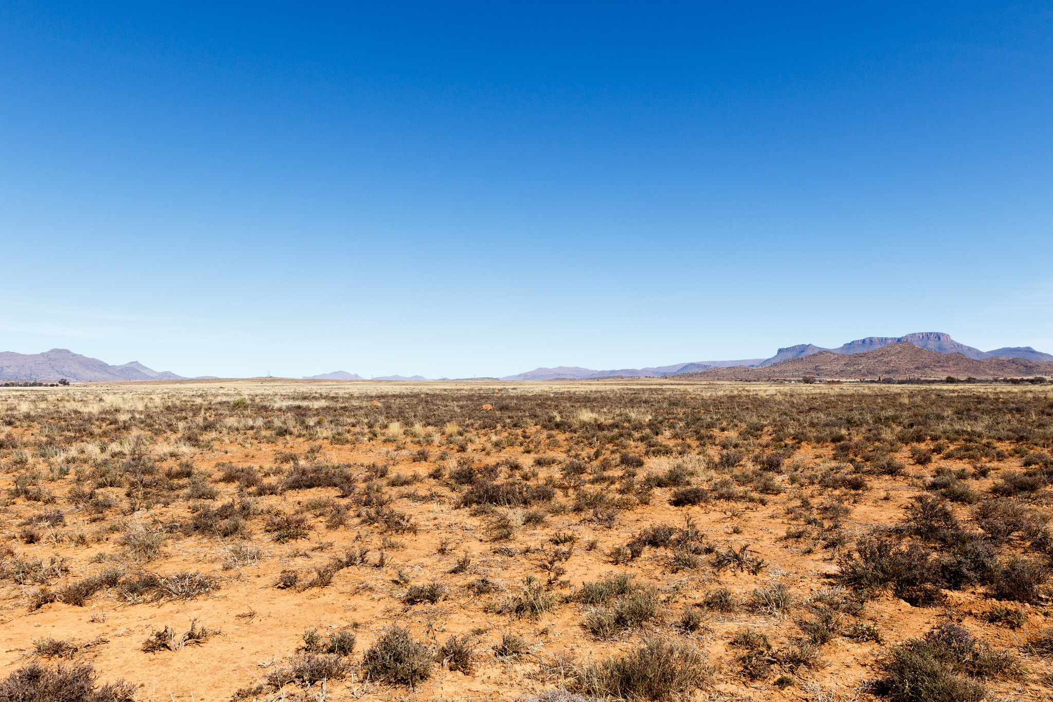 Canon EOS 7D Mark II + Canon EF 300mm f/2.8L sample photo. Barren field with mountains and blue sky photography